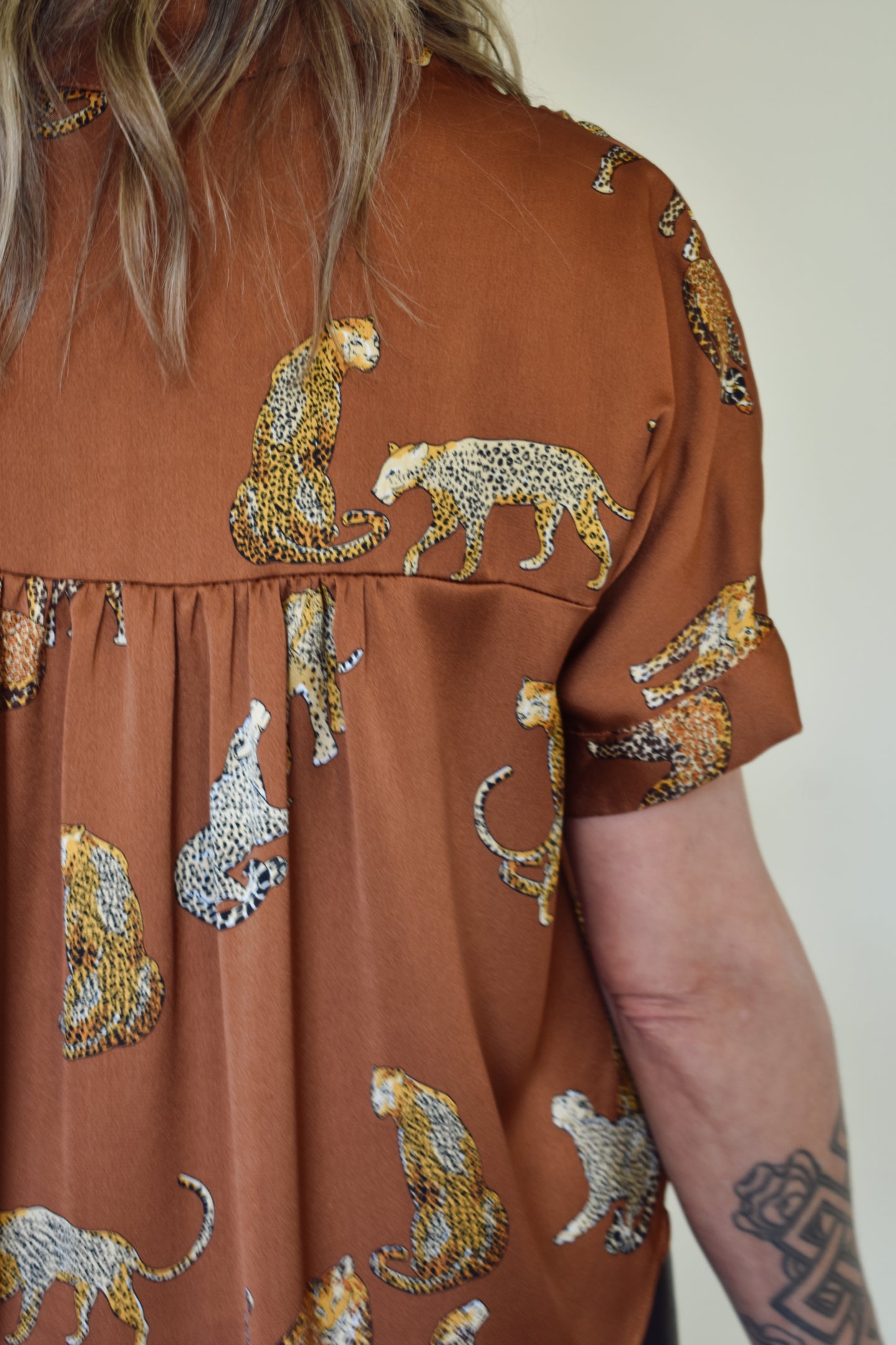 Satin drop shoulder short sleeve button down with rounded hem. flowy fit, not oversized. copper color with leopards