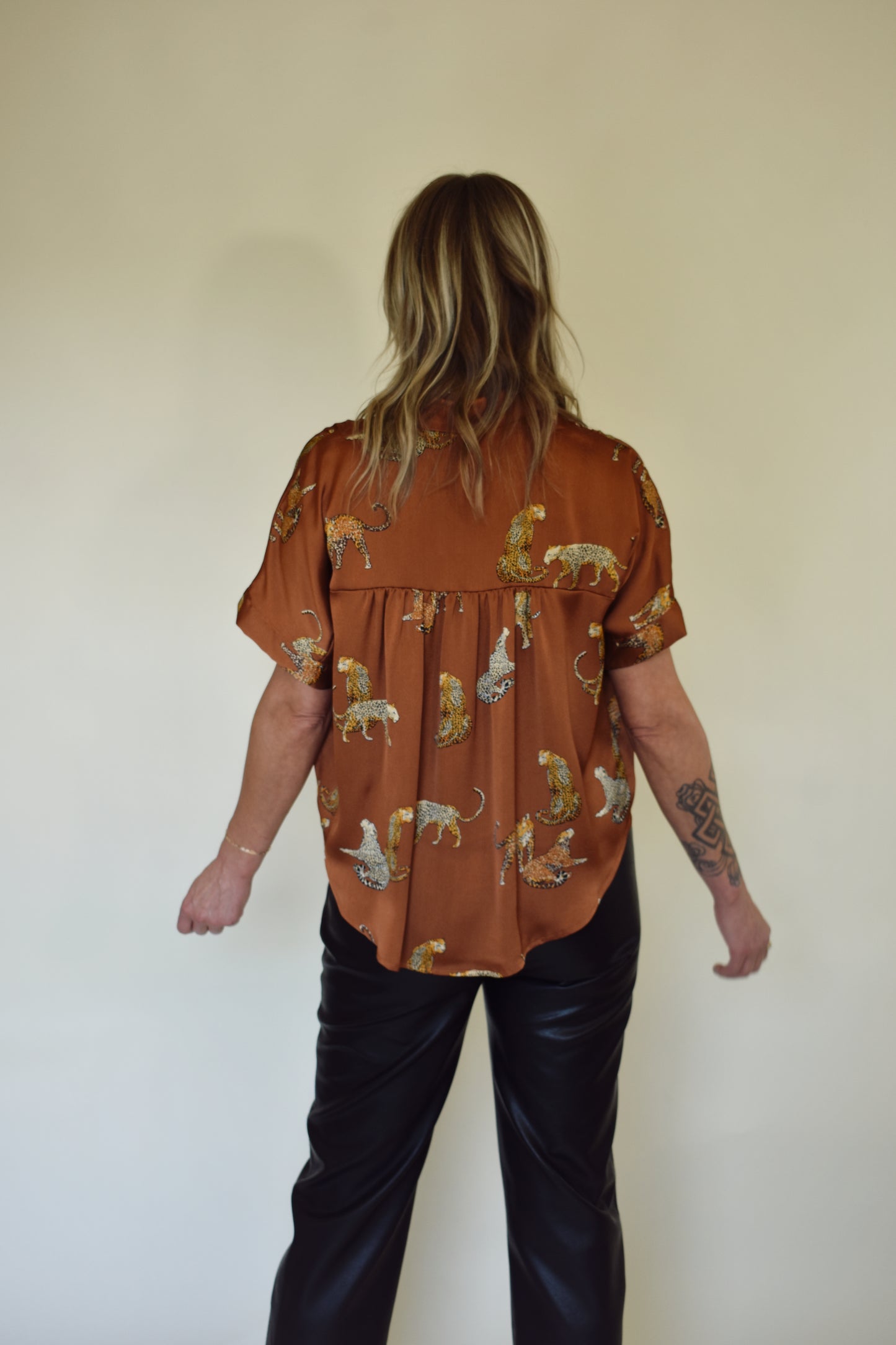 Satin drop shoulder short sleeve button down with rounded hem. flowy fit, not oversized. copper color with leopards