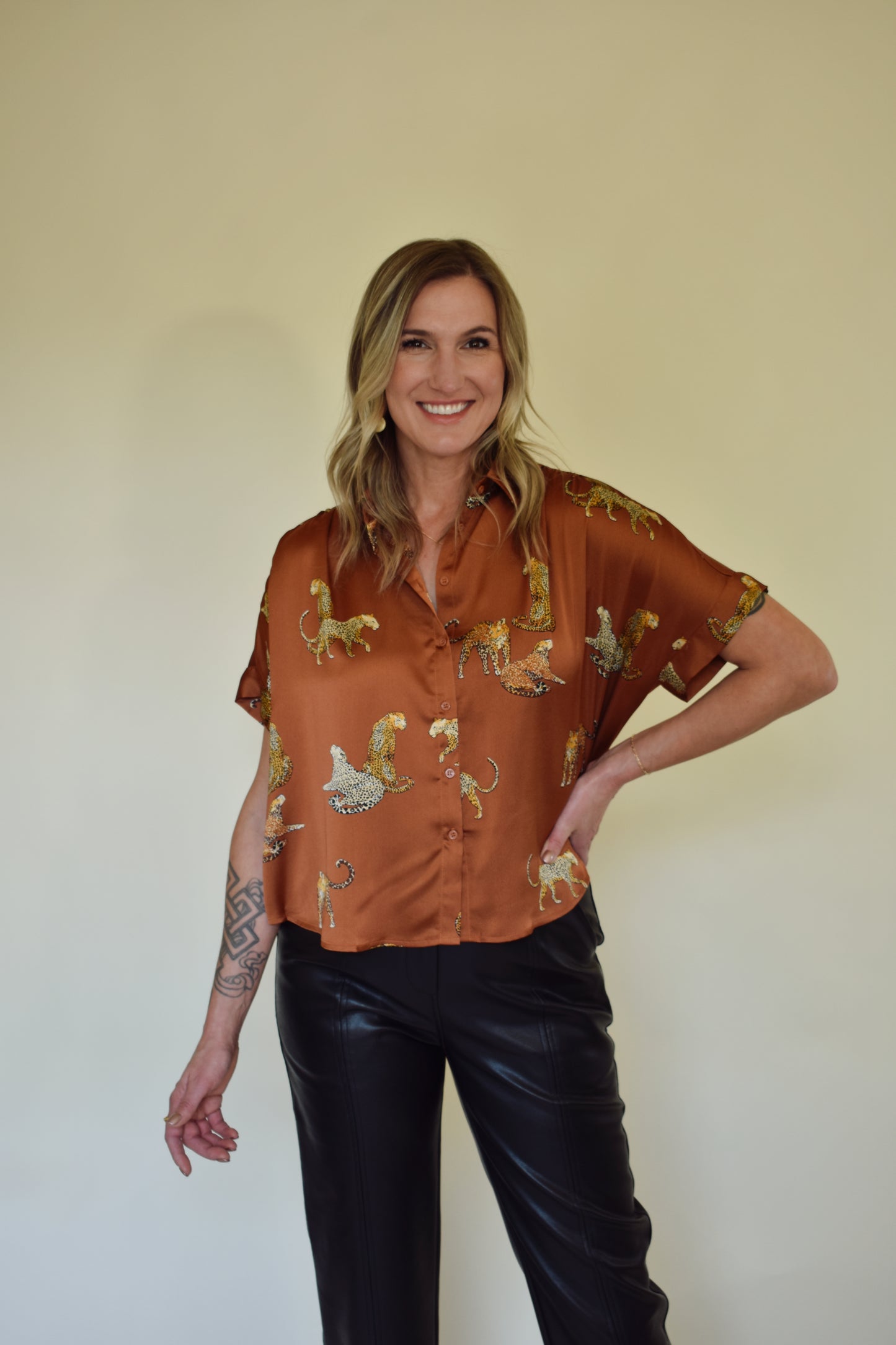 Satin drop shoulder short sleeve button down with rounded hem. flowy fit, not oversized. copper color with leopards