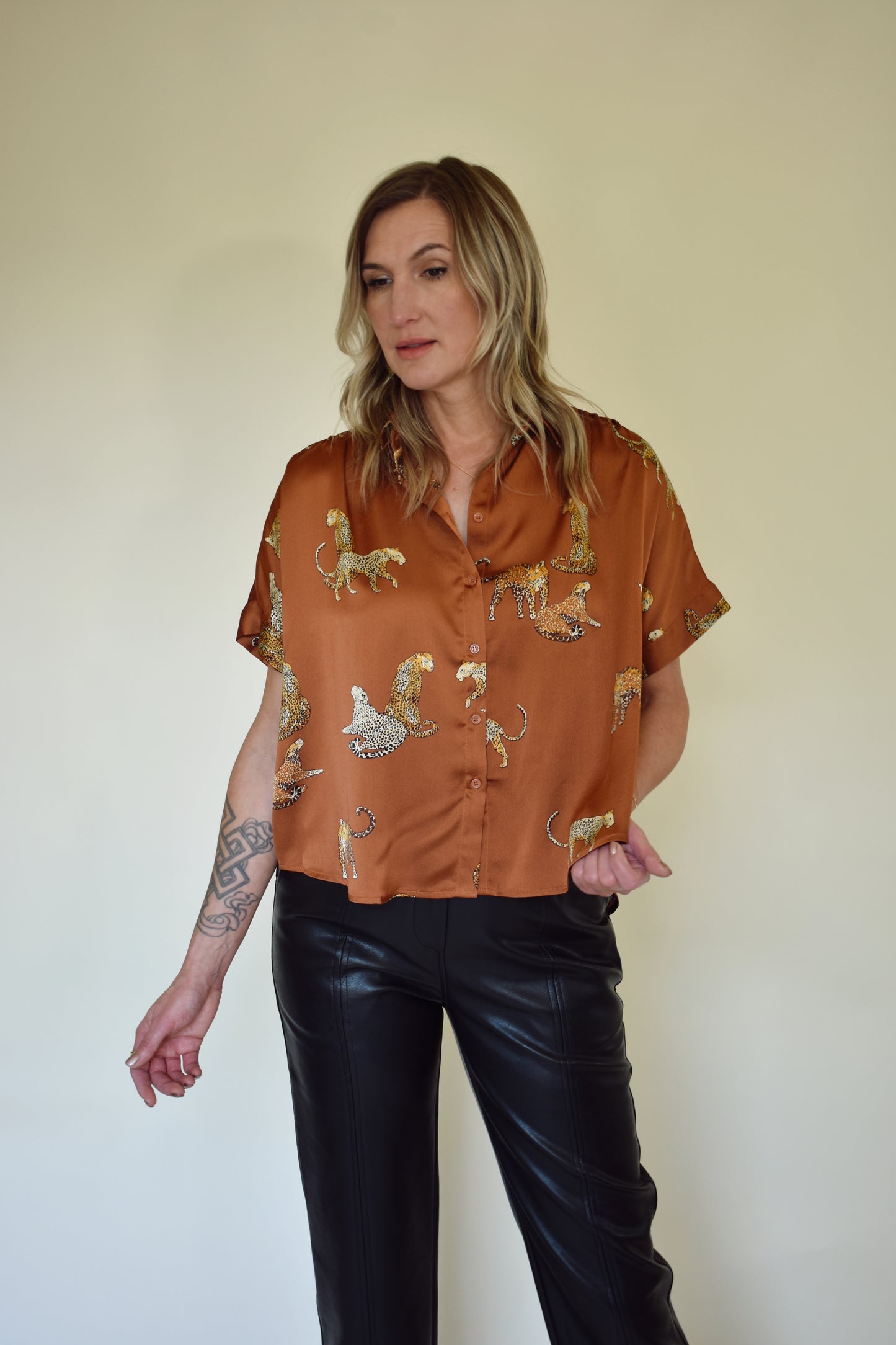 Satin drop shoulder short sleeve button down with rounded hem. flowy fit, not oversized. copper color with leopards