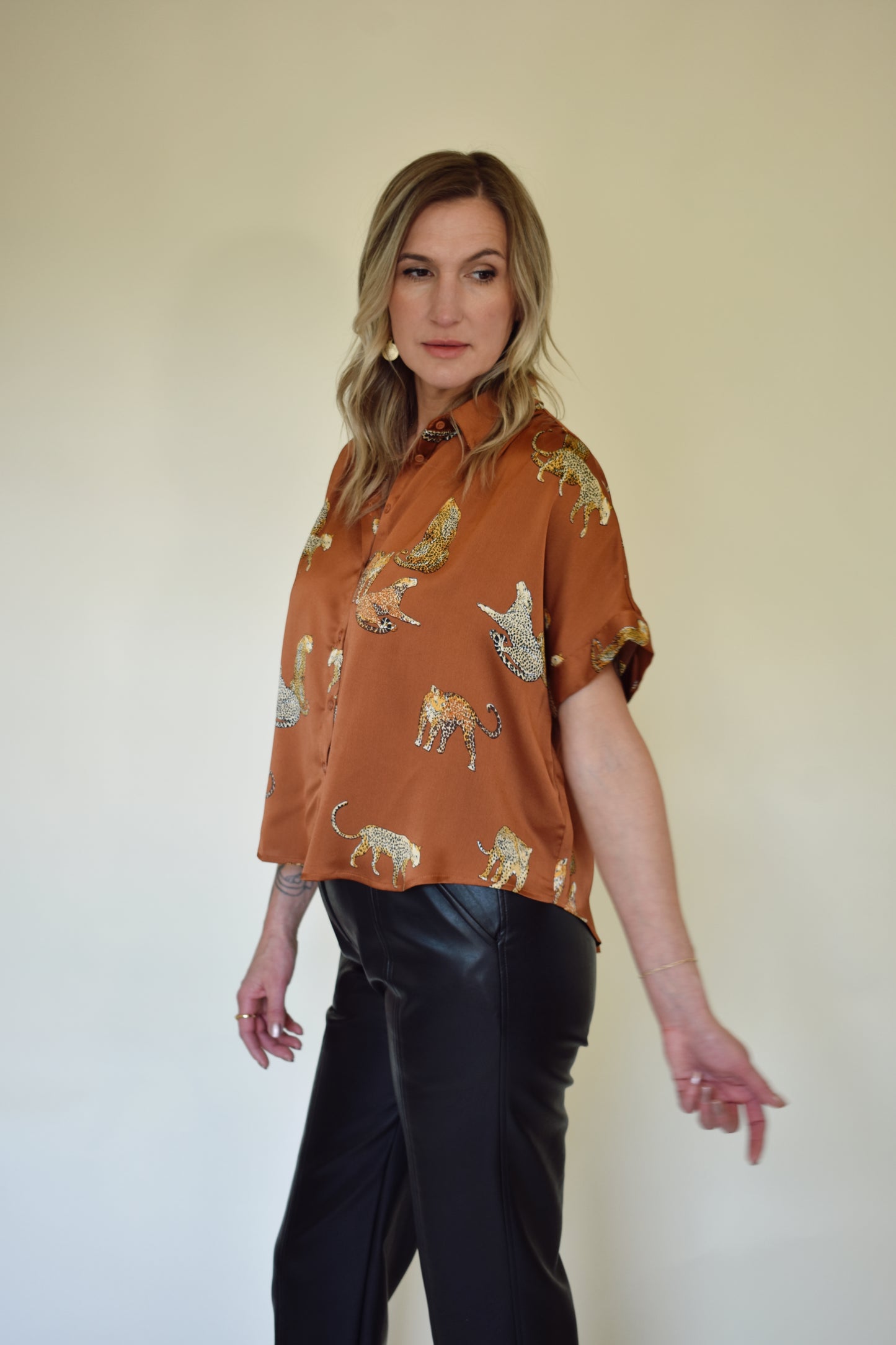 Satin drop shoulder short sleeve button down with rounded hem. flowy fit, not oversized. copper color with leopards