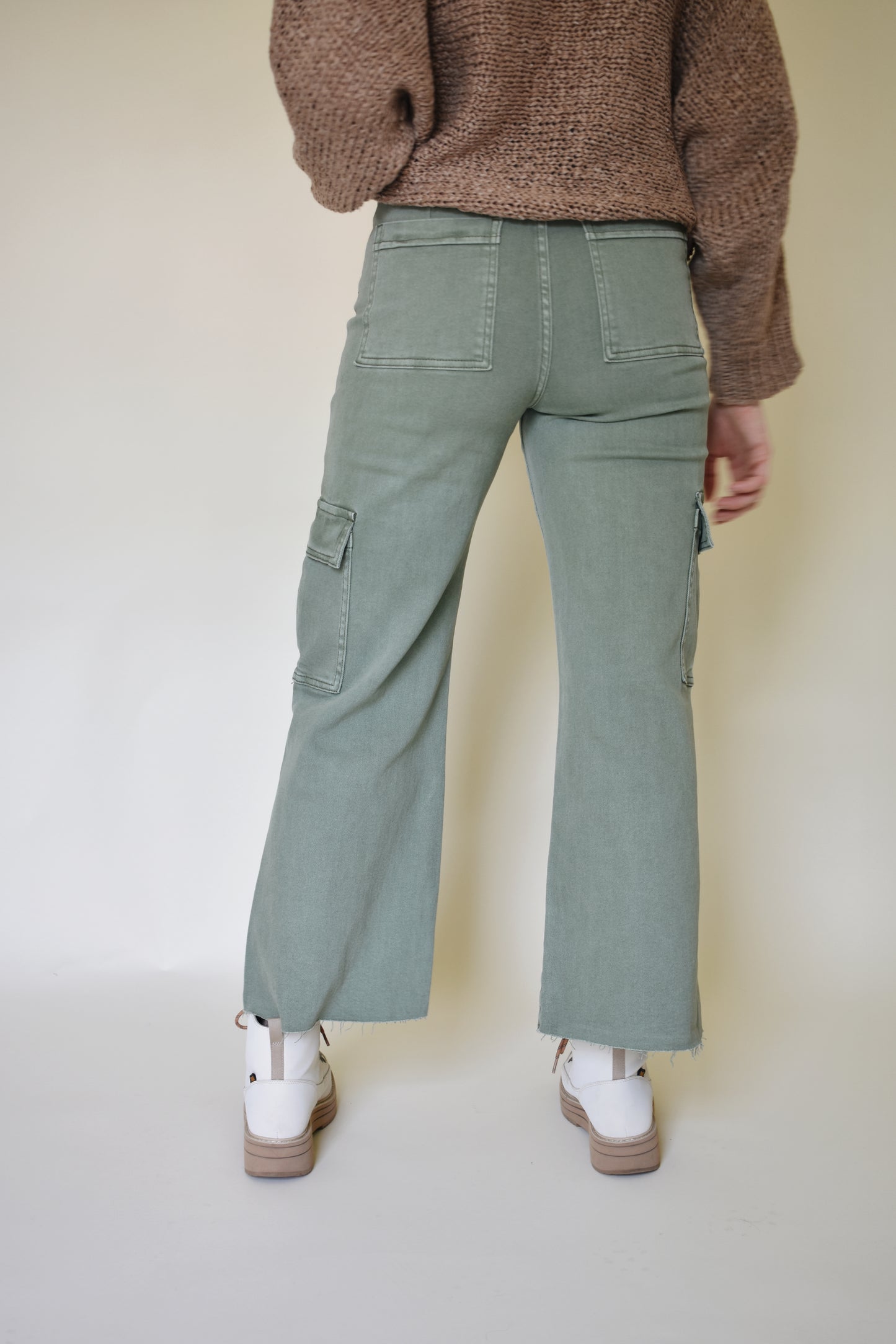 Wide leg cargo pants with pockets on side with flap and on the back. Button enclosure with belt loops. Raw hem. Sage green color.