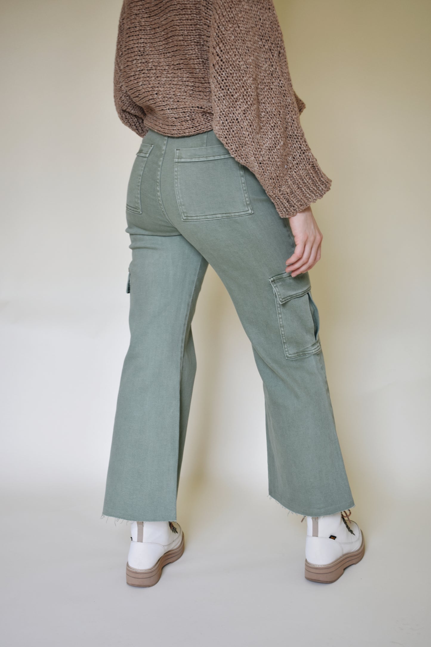 Wide leg cargo pants with pockets on side with flap and on the back. Button enclosure with belt loops. Raw hem. Sage green color.