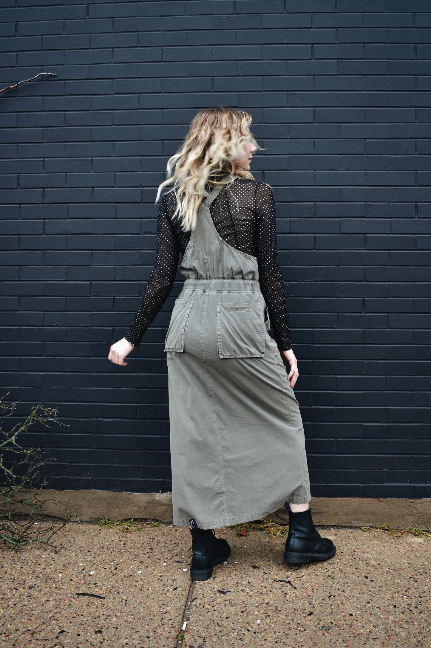 olive overall dress, midi length, adjustable straps, waist drawstring, front slit up skirt, front and back patch pockets, and a pocket on the front.