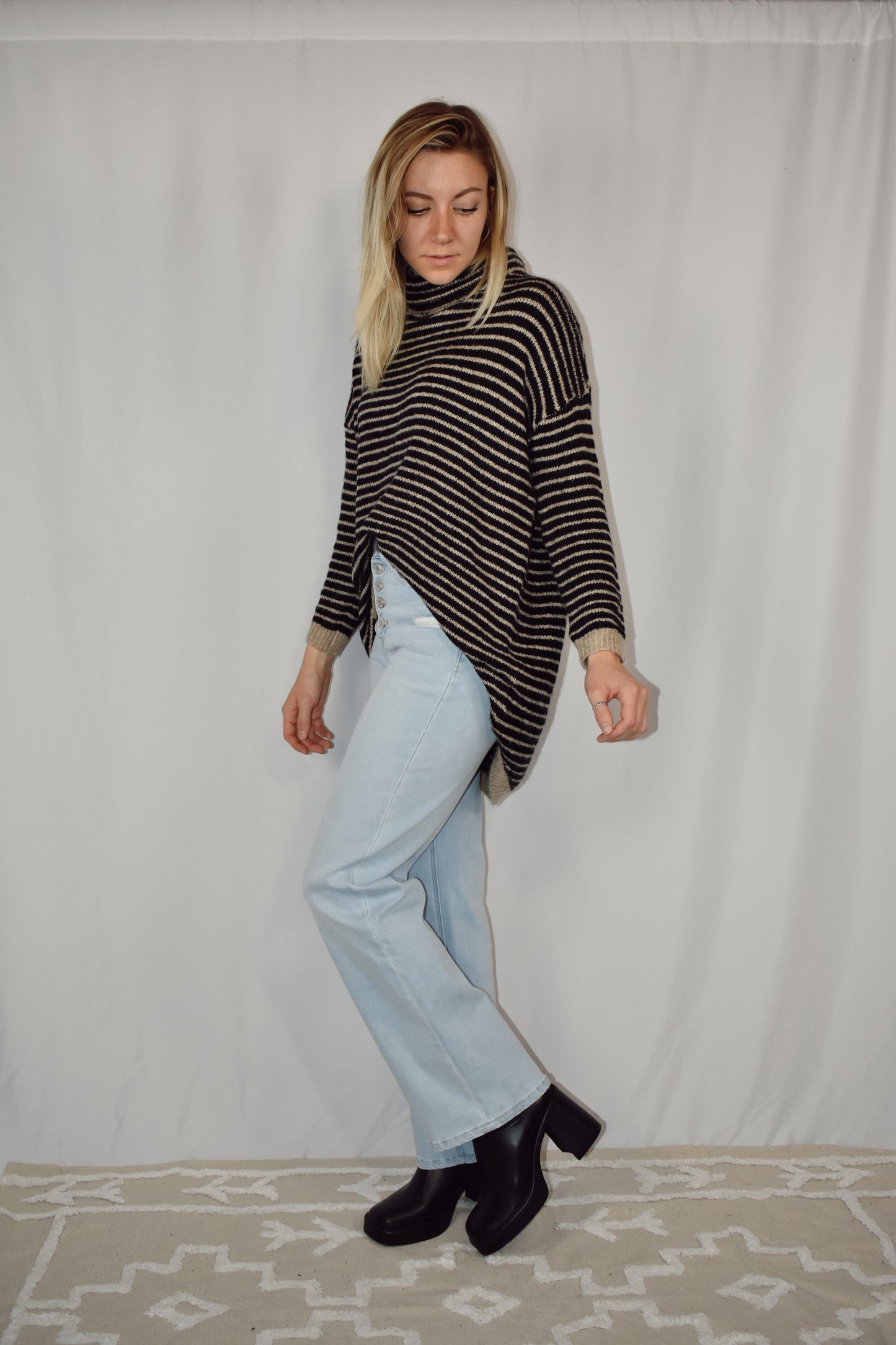 Pullover turtleneck striped sweater. Drop shoulder long sleeves, ribbed hem and sleeve cuffs, and high-low rounded hem. Black and taupe color.