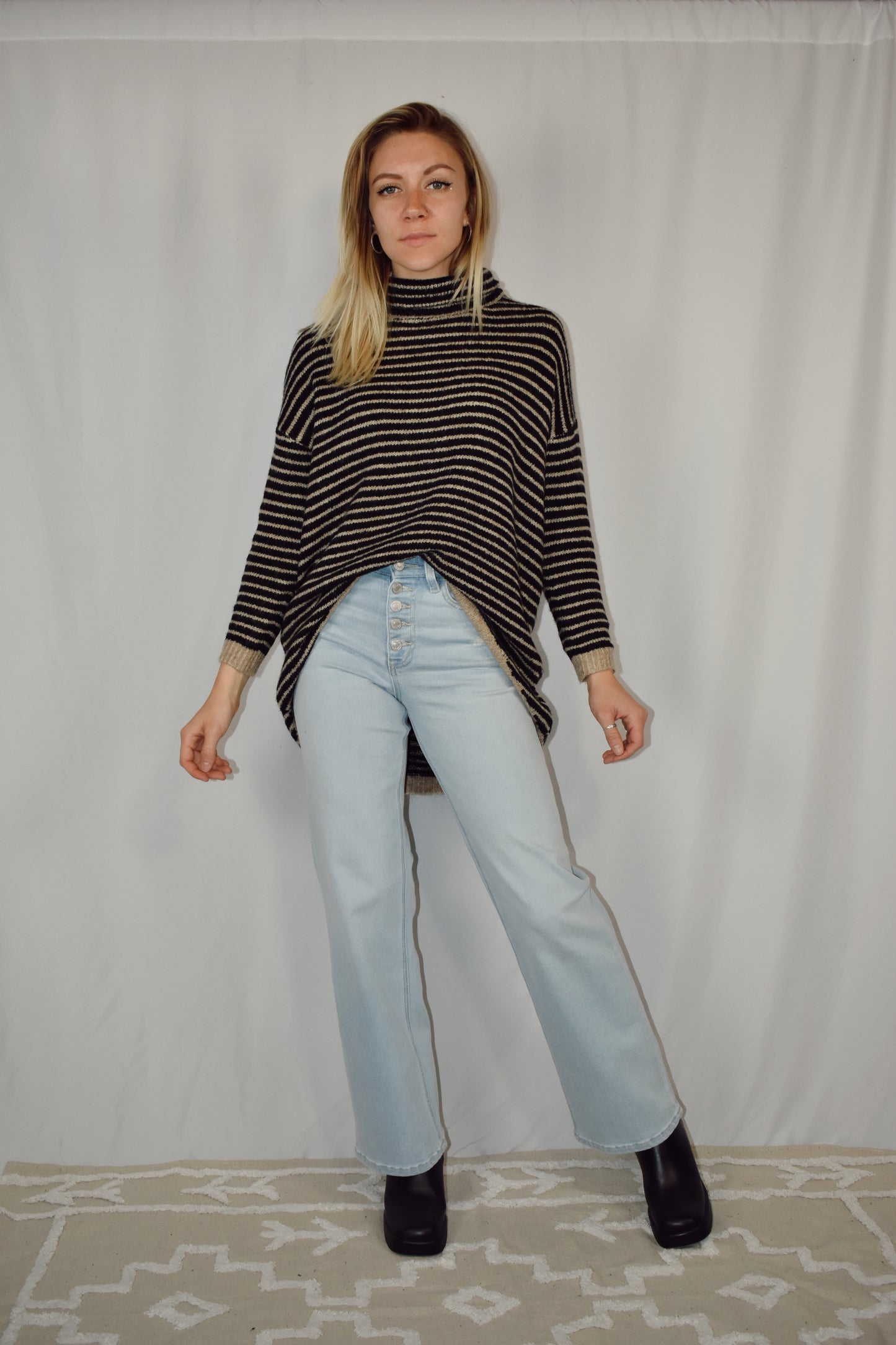 Pullover turtleneck striped sweater. Drop shoulder long sleeves, ribbed hem and sleeve cuffs, and high-low rounded hem. Black and taupe.