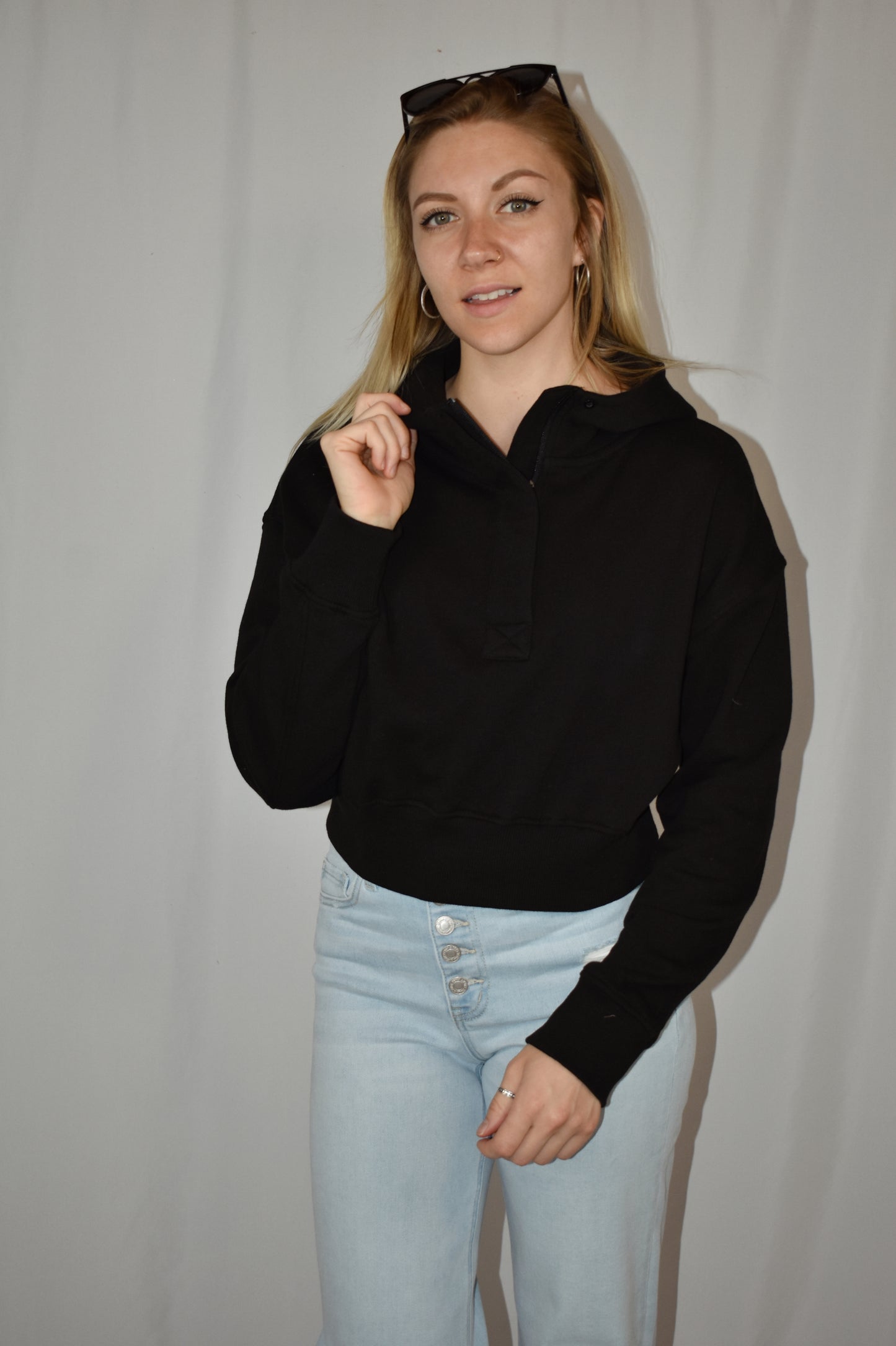 Cropped black hoodie with half placket zip with button closure at neckline. Ribbed cuffs and fleece lining.