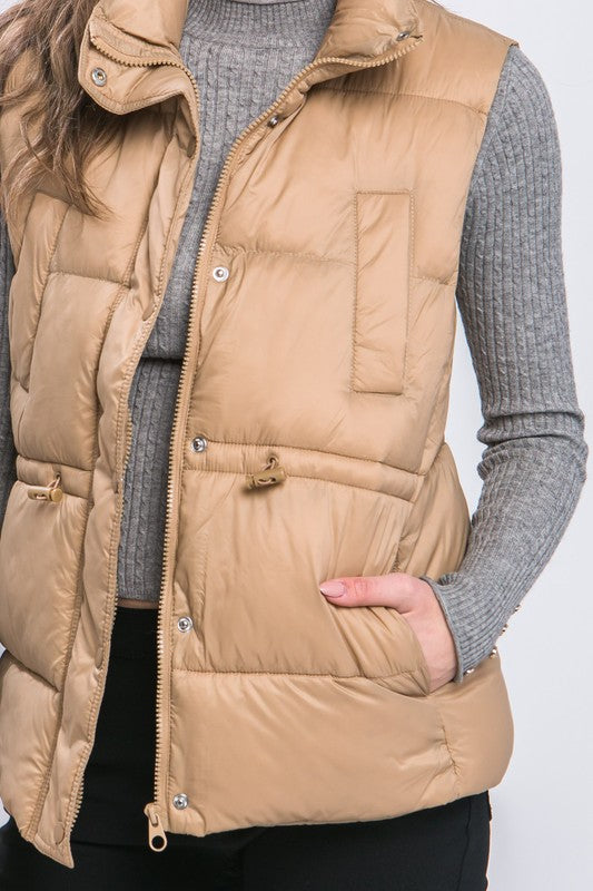 Lightweight zip up puffer vest with sinch drawstring around waist for adjustable fit. 4 pockets.