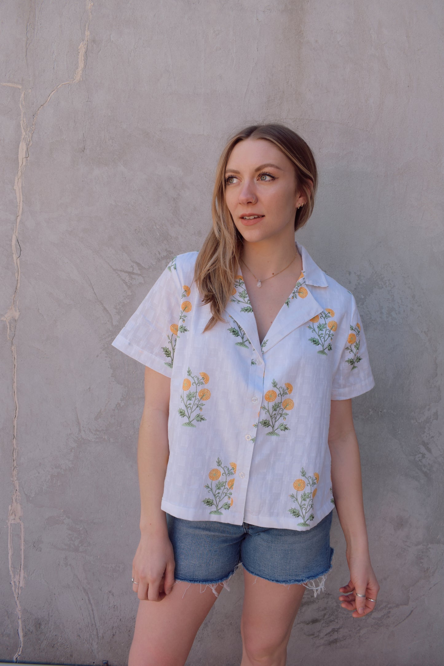 white v neck short sleeve button down with a marigold embroidered pattern. full length, straight fit. 100% cotton