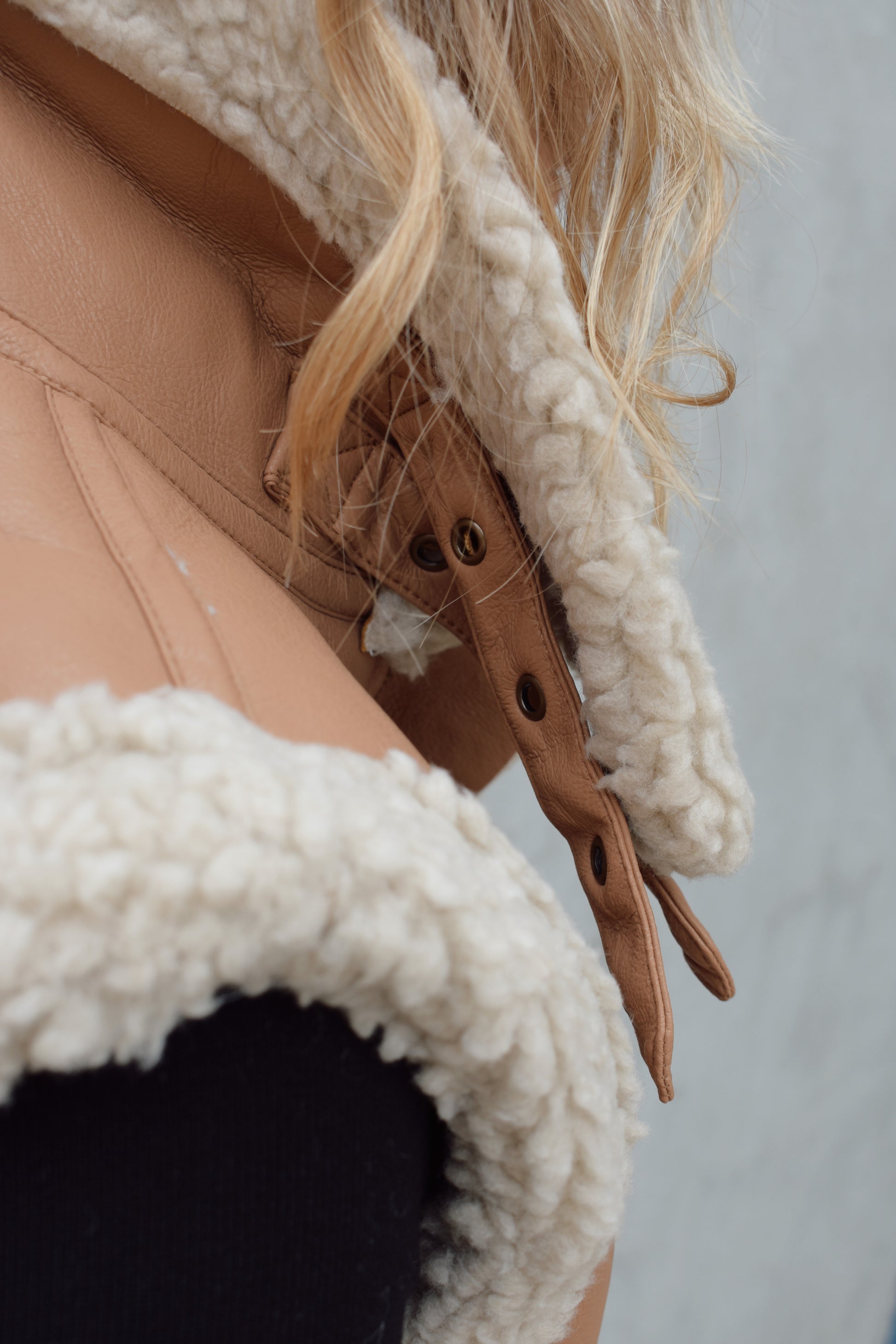 ivory sherpa lined faux camel colored leather moto vest with fold over collar, sherpa exposed along hem and collar, zip enclosure, has pockets, slightly cropped