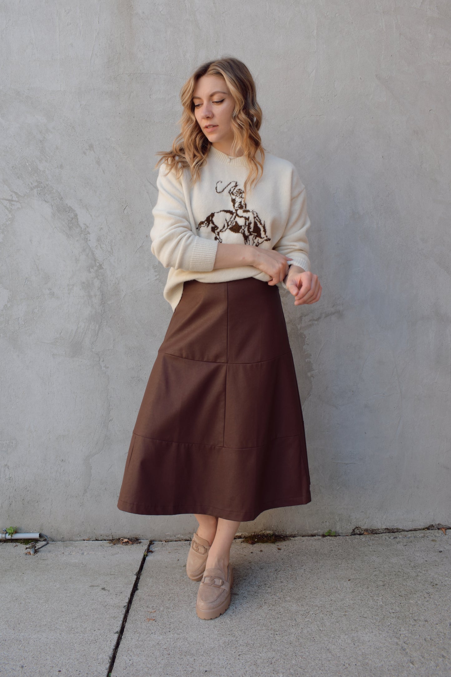 cream colored crew neck sweater relaxed fit full length with cowboy design in brown on front ribbed cuffs hem and neckline