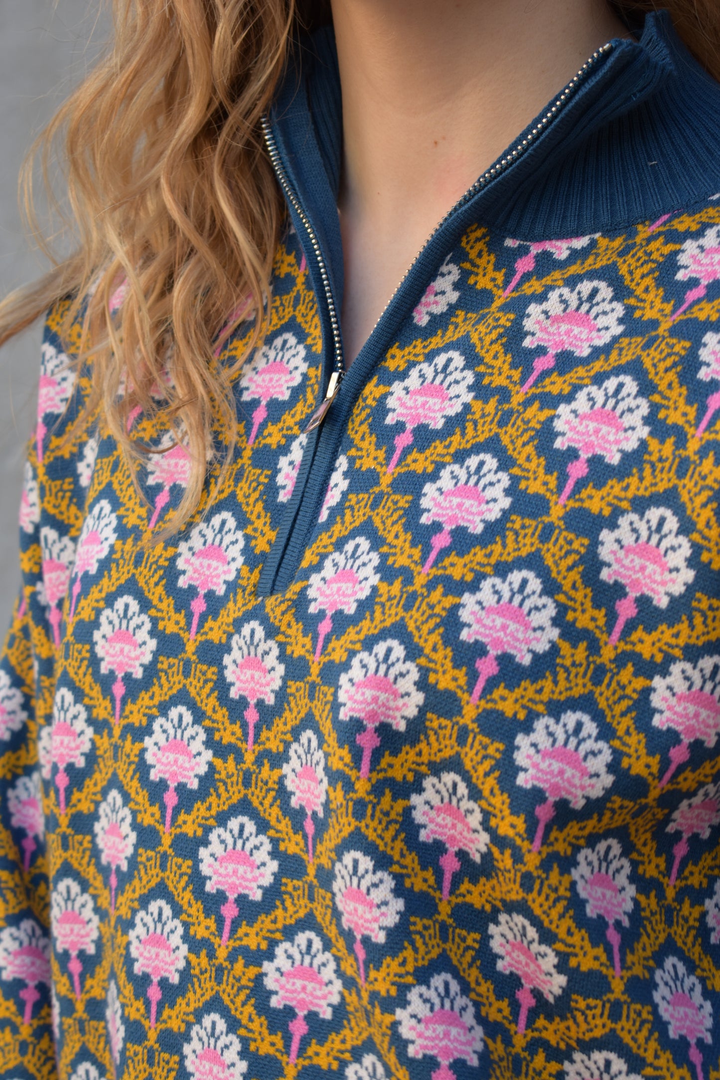 half zip relaxed fit statement pattern pullover with blue and yellow band at ham and cuff and just blue on collar. pattern is yellow, white, and pink on a blue background