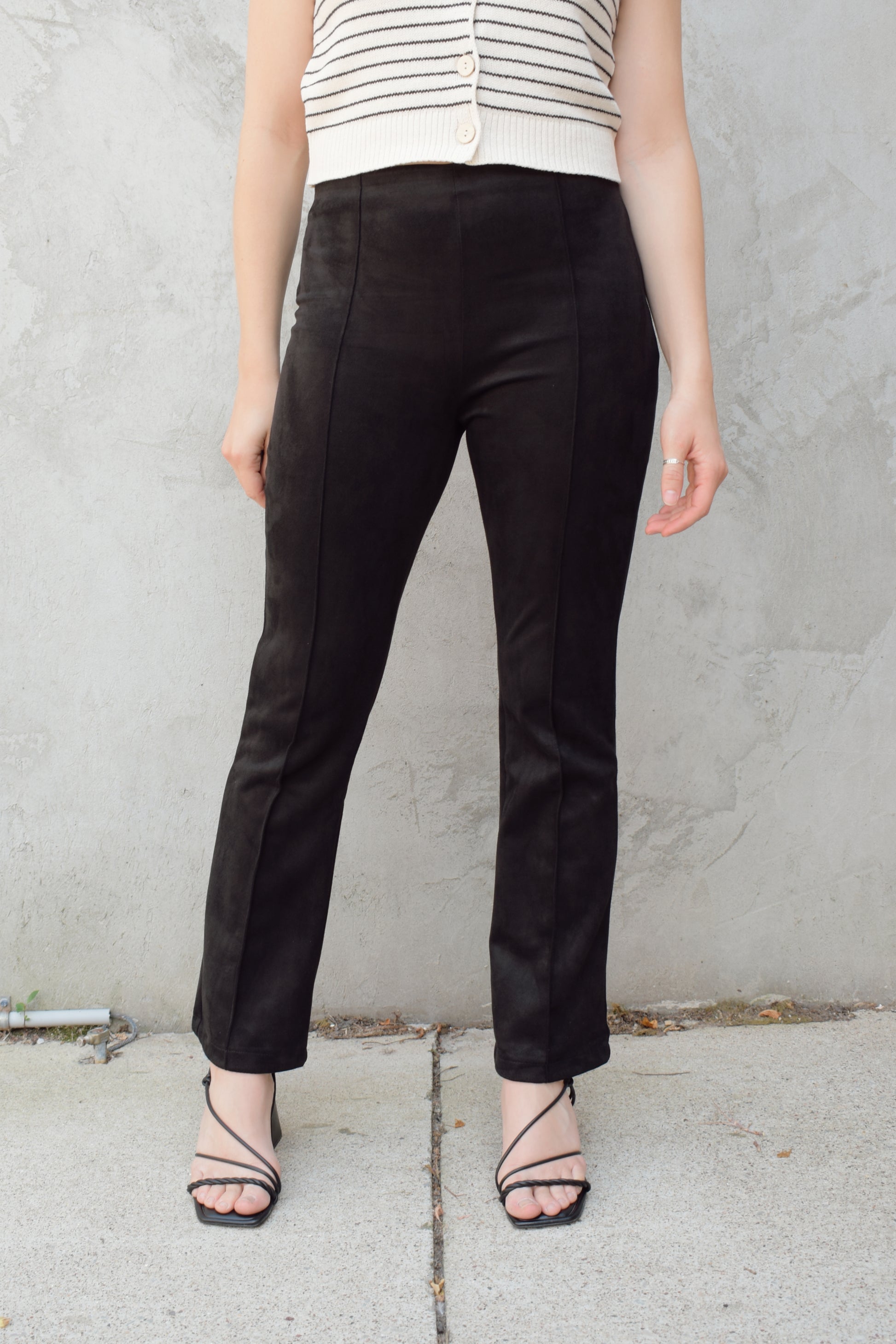 black faux suede pants with a slight cropped kick flare, raised seam detail along front of pant legs, zip side enclosure, high waisted