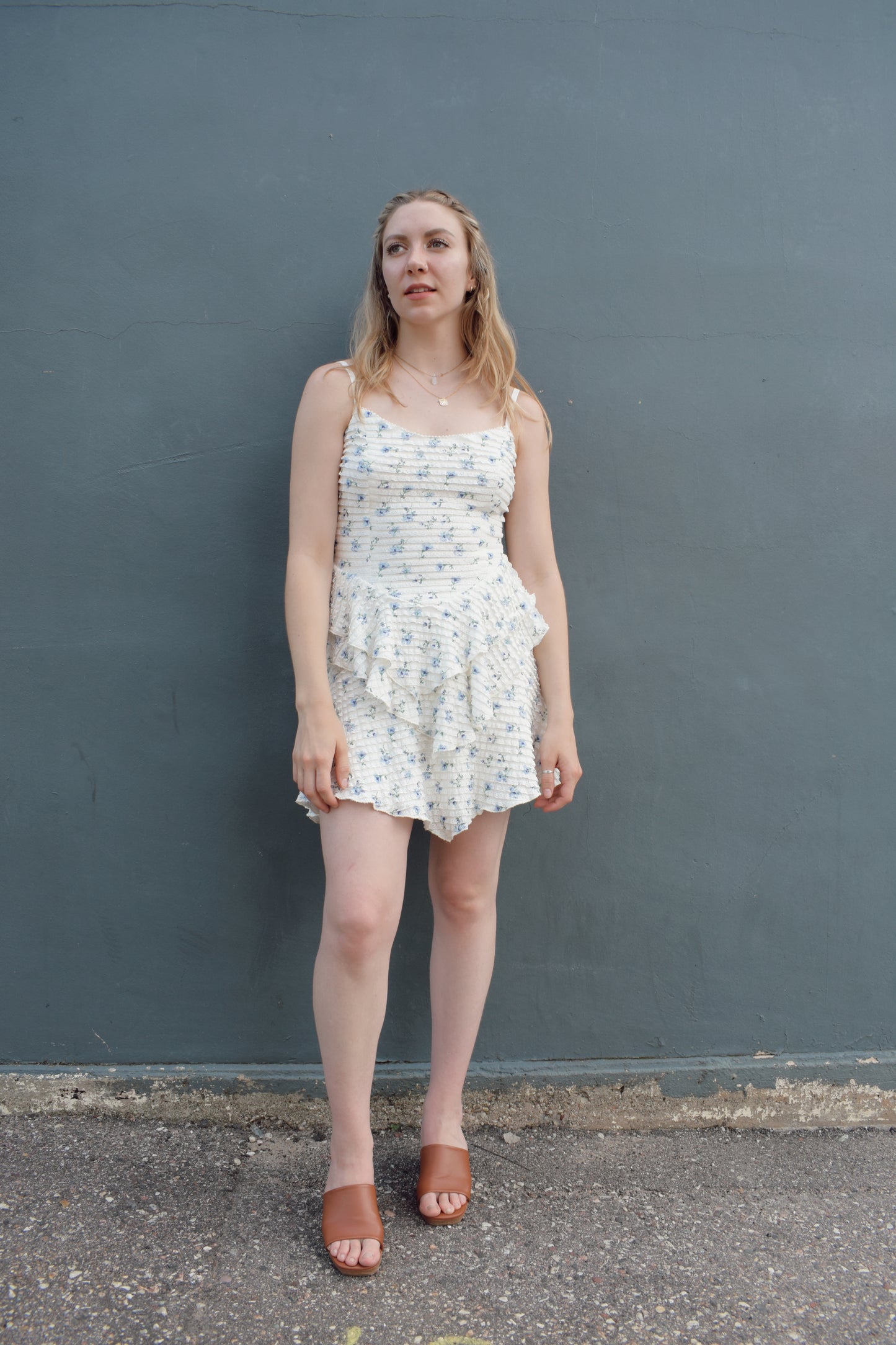 cream mini dress with a blue ditsy floral pattern and mini ruffle fabric, stretchy, back zip enclosure, adjustable spaghetti straps, shark bite tiered skirt, fitted bodice, lined