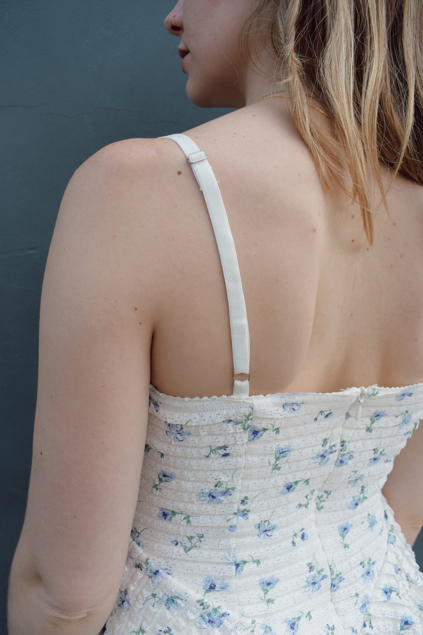 cream mini dress with a blue ditsy floral pattern and mini ruffle fabric, stretchy, back zip enclosure, adjustable spaghetti straps, shark bite tiered skirt, fitted bodice, lined