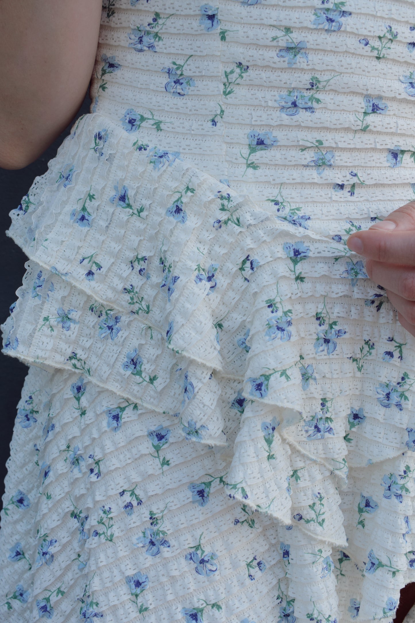 cream mini dress with a blue ditsy floral pattern and mini ruffle fabric, stretchy, back zip enclosure, adjustable spaghetti straps, shark bite tiered skirt, fitted bodice, lined