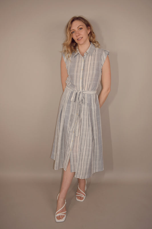 white button down midi dress with blue vertical stripes. cap short sleeves with cuff and button on top of the shoulder. skirt has extra fabric that comes together and ties in the front making skirt more full and flowy.  back has synching at waist with cut out that meets waist band.