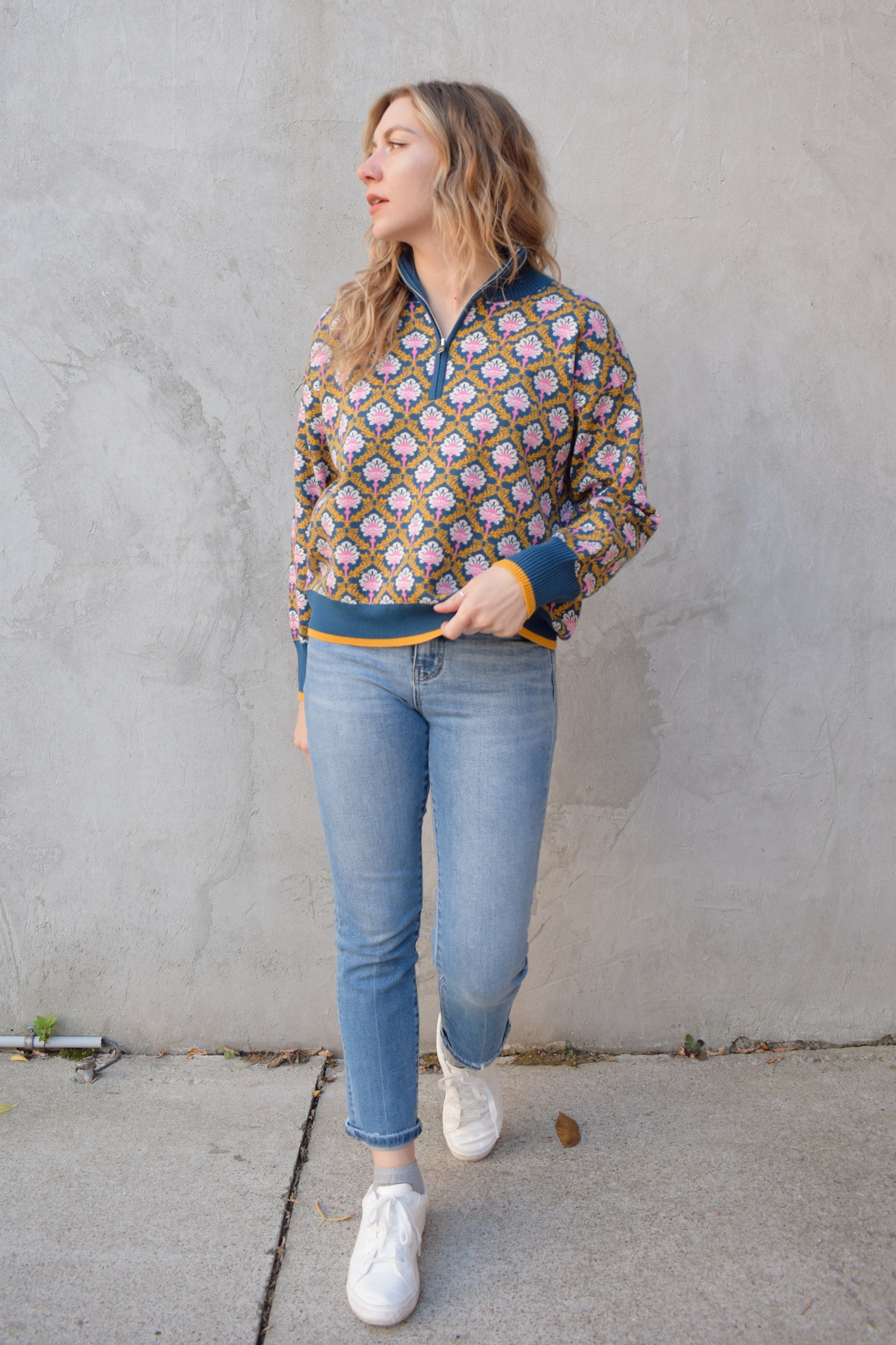 half zip relaxed fit statement pattern pullover with blue and yellow band at ham and cuff and just blue on collar. pattern is yellow, white, and pink on a blue background