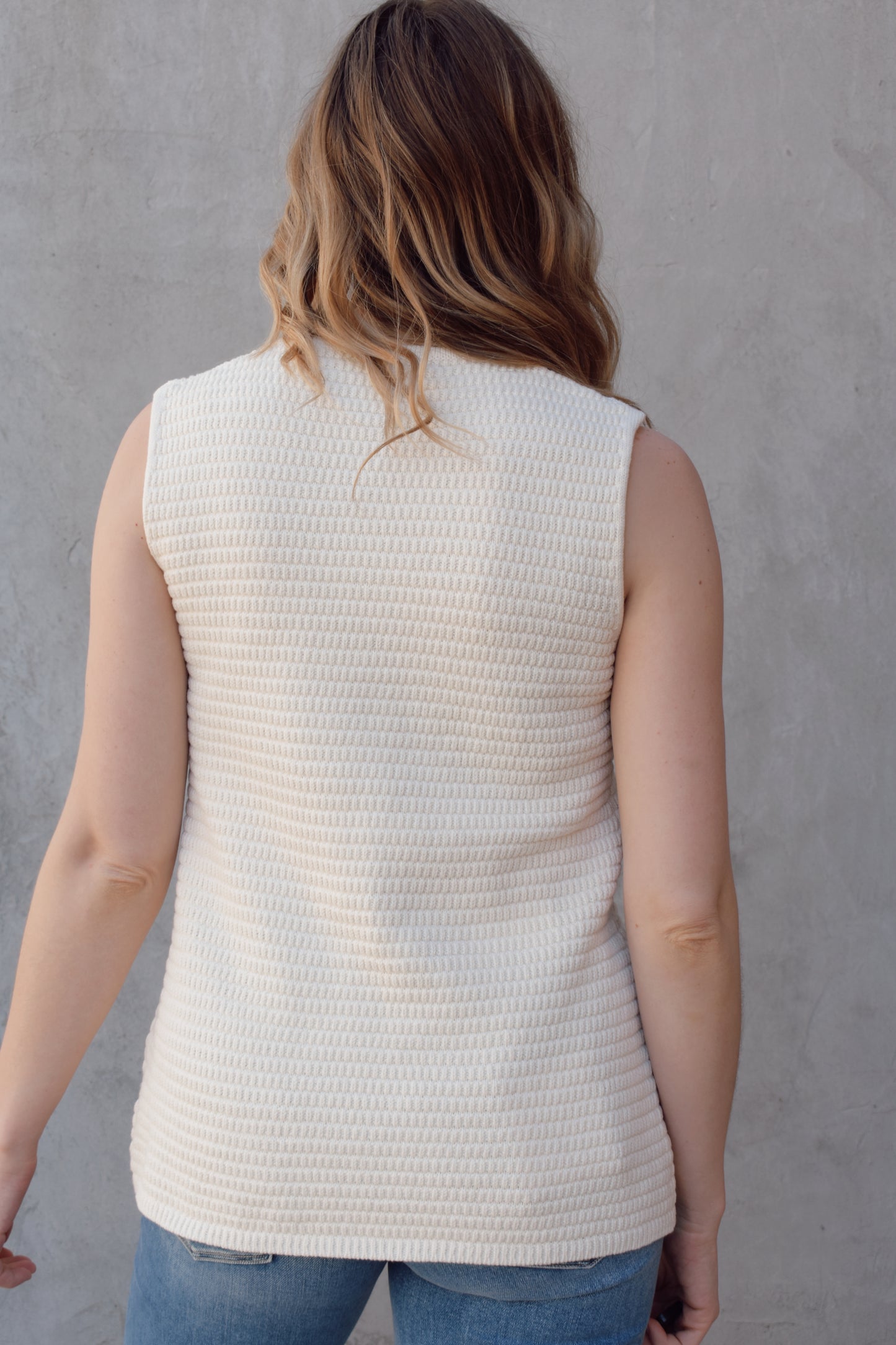 cream full length knit summer sweater vest with front slit and brown button enclosure crew neck when fully buttoned patch pockets with front button detail