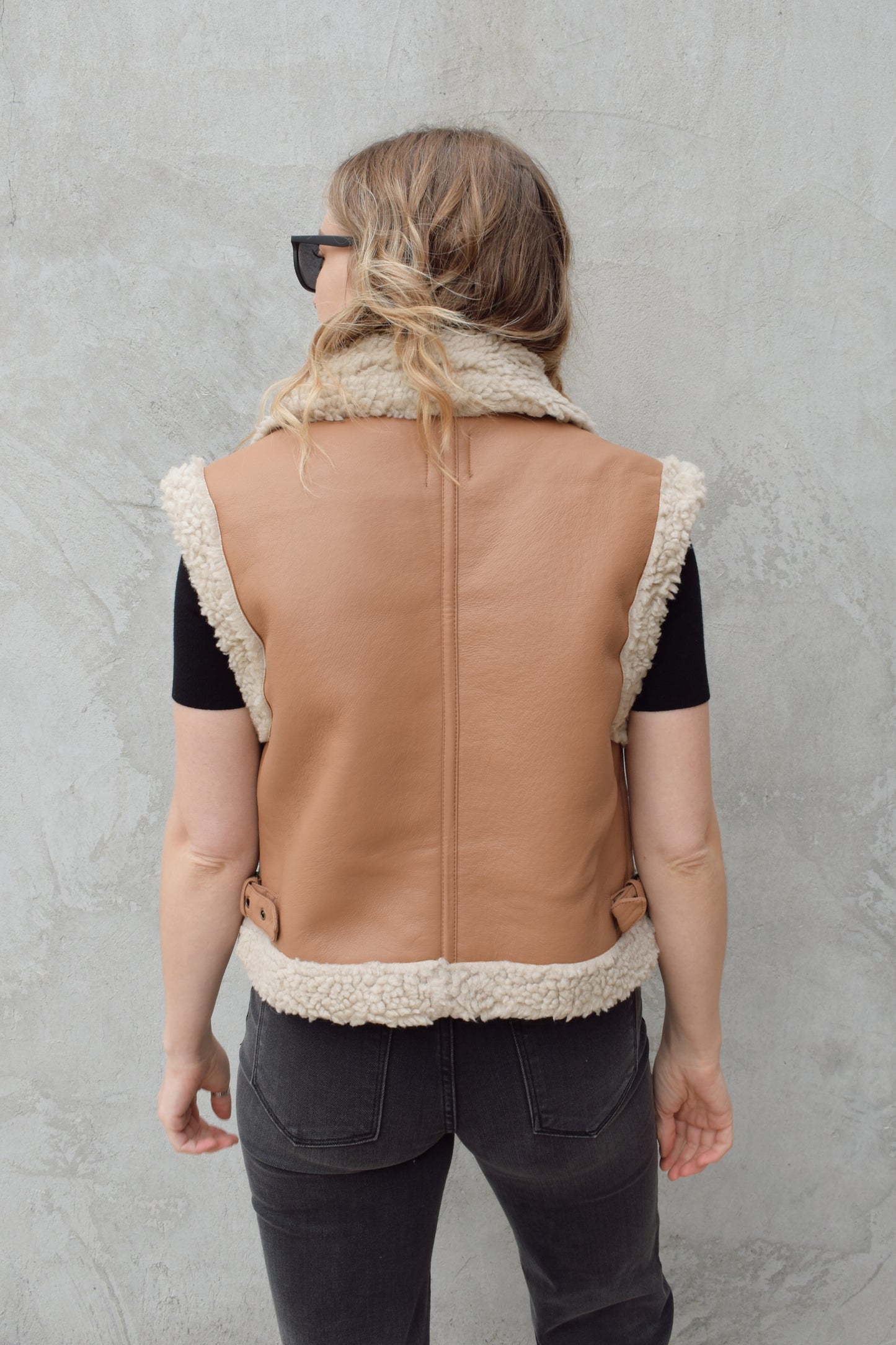 ivory sherpa lined faux camel colored leather moto vest with fold over collar, sherpa exposed along hem and collar, zip enclosure, has pockets, slightly cropped