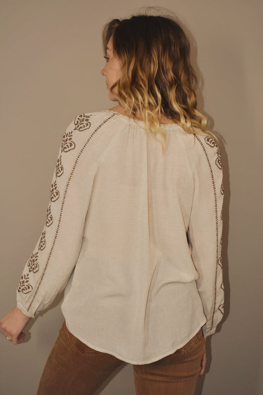 Cream colored v neck full length tunic with brown embroidered detailing down sides of arms and along hem that goes down the center front of the shirt. Flowy. Boho. 