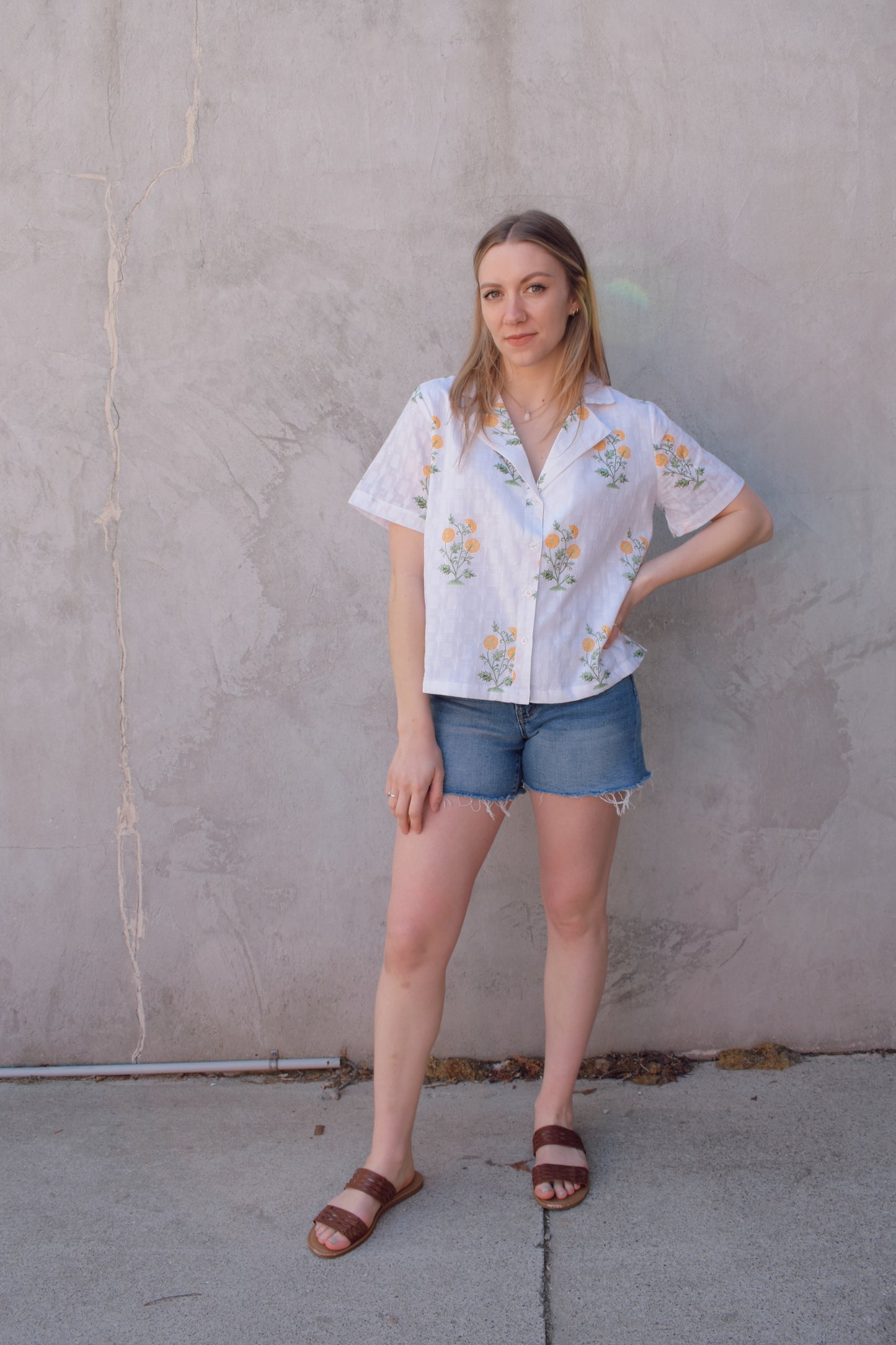 white v neck short sleeve button down with a marigold embroidered pattern. full length, straight fit. 100% cotton