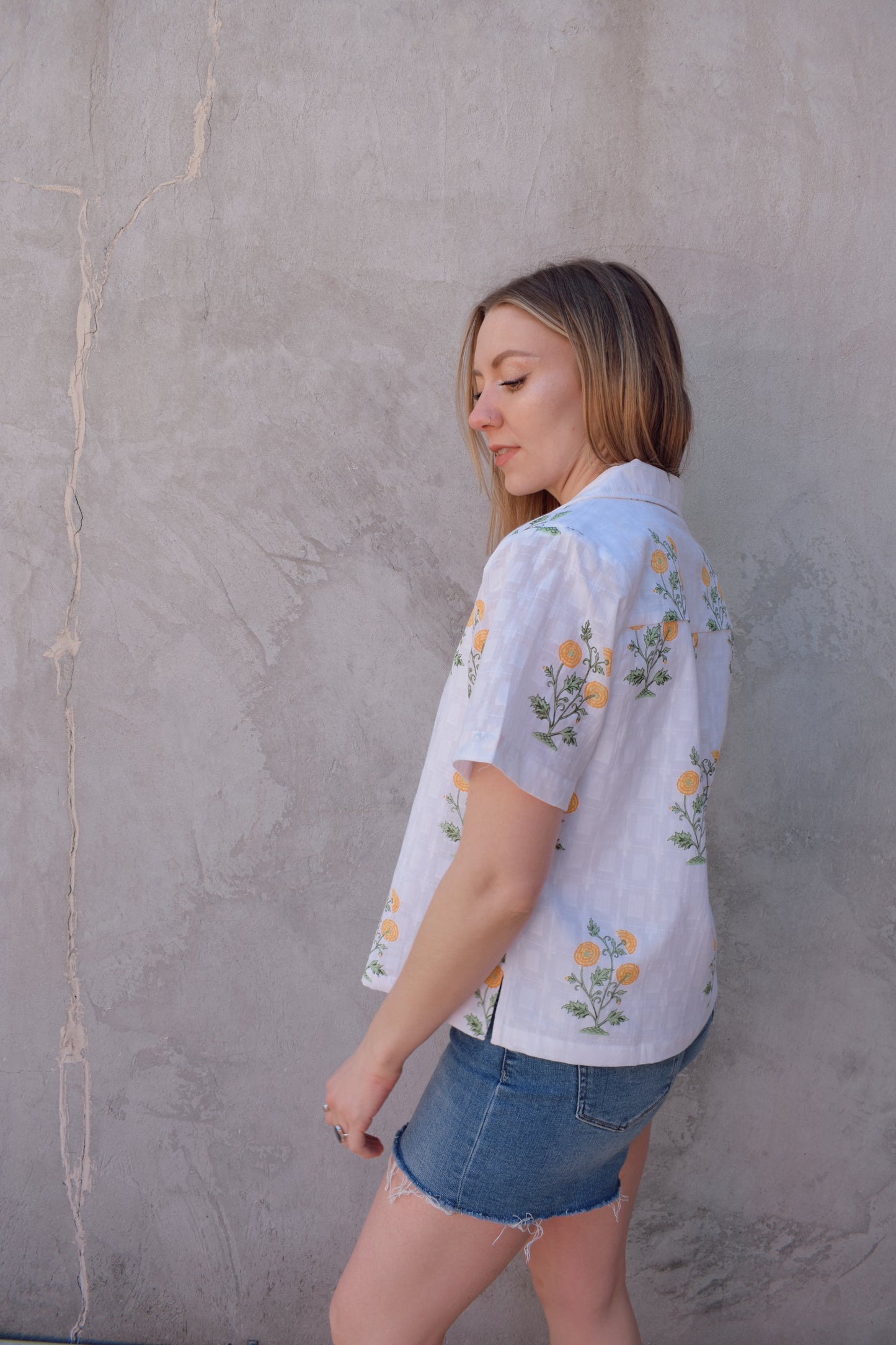 white v neck short sleeve button down with a marigold embroidered pattern. full length, straight fit. 100% cotton
