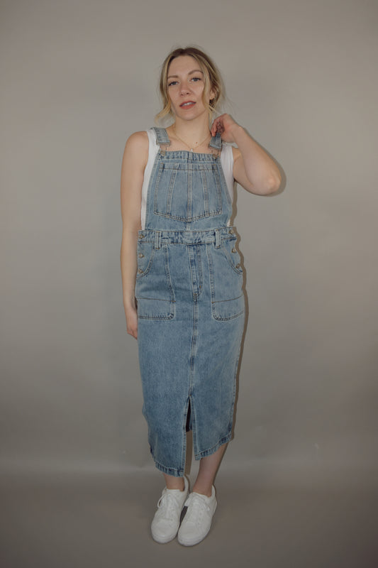 light wash denim overall midi skirt dress with front slit, square neckline on front and back, adjustable straps, has beltloops, deep front pockets, back pockets, button enclosure on both sides
