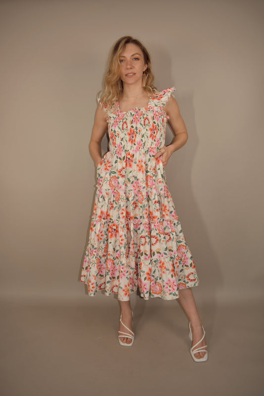 floral midi dress with tiered skirt and ruffle straps with smocking. smocked bodice. square neck and back. greens, pinks, yellow and orange colors for pattern.