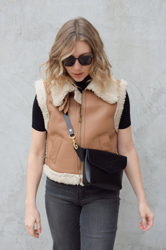 ivory sherpa lined faux camel colored leather moto vest with fold over collar, sherpa exposed along hem and collar, zip enclosure, has pockets, slightly cropped