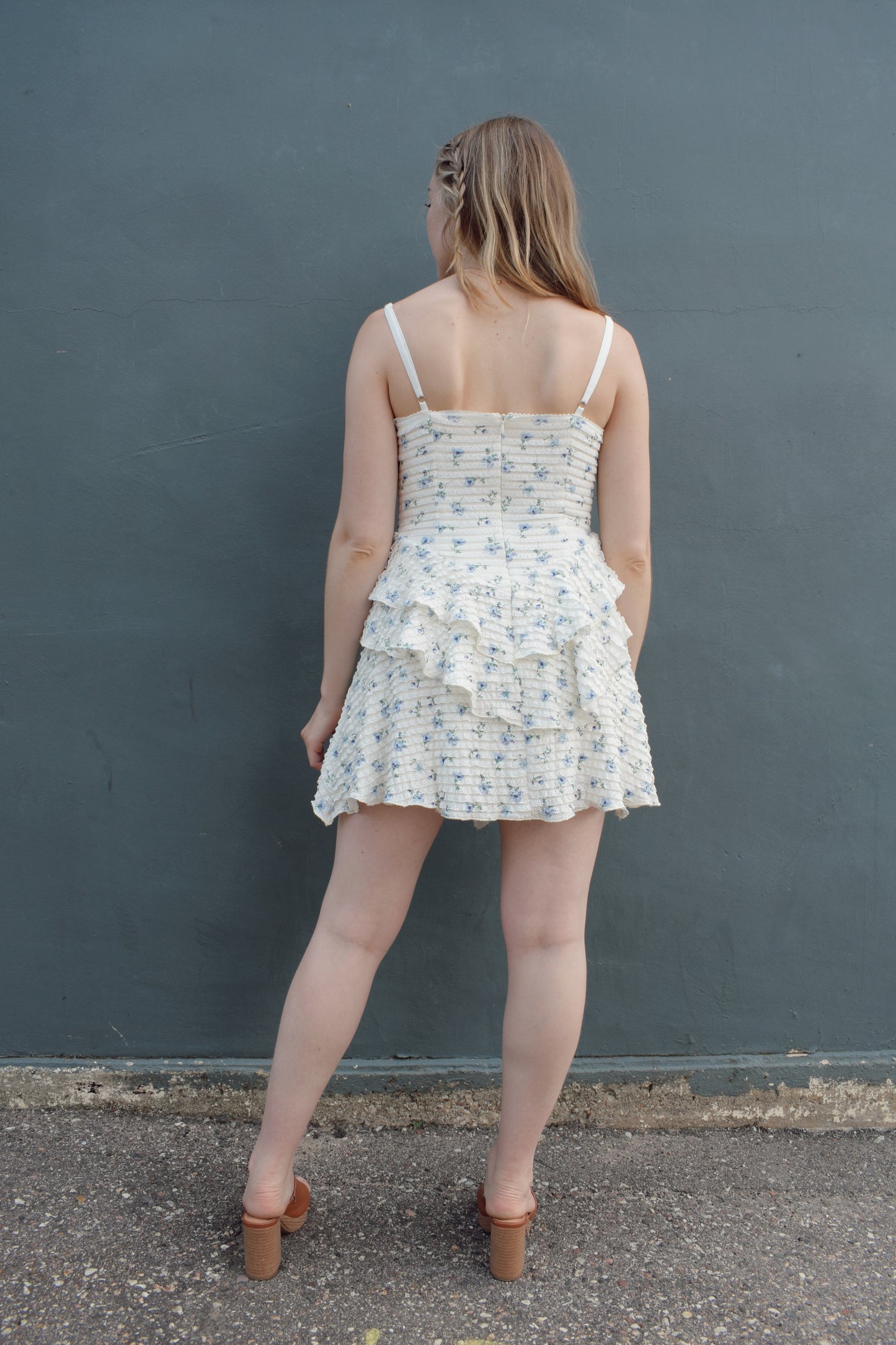 cream mini dress with a blue ditsy floral pattern and mini ruffle fabric, stretchy, back zip enclosure, adjustable spaghetti straps, shark bite tiered skirt, fitted bodice, lined