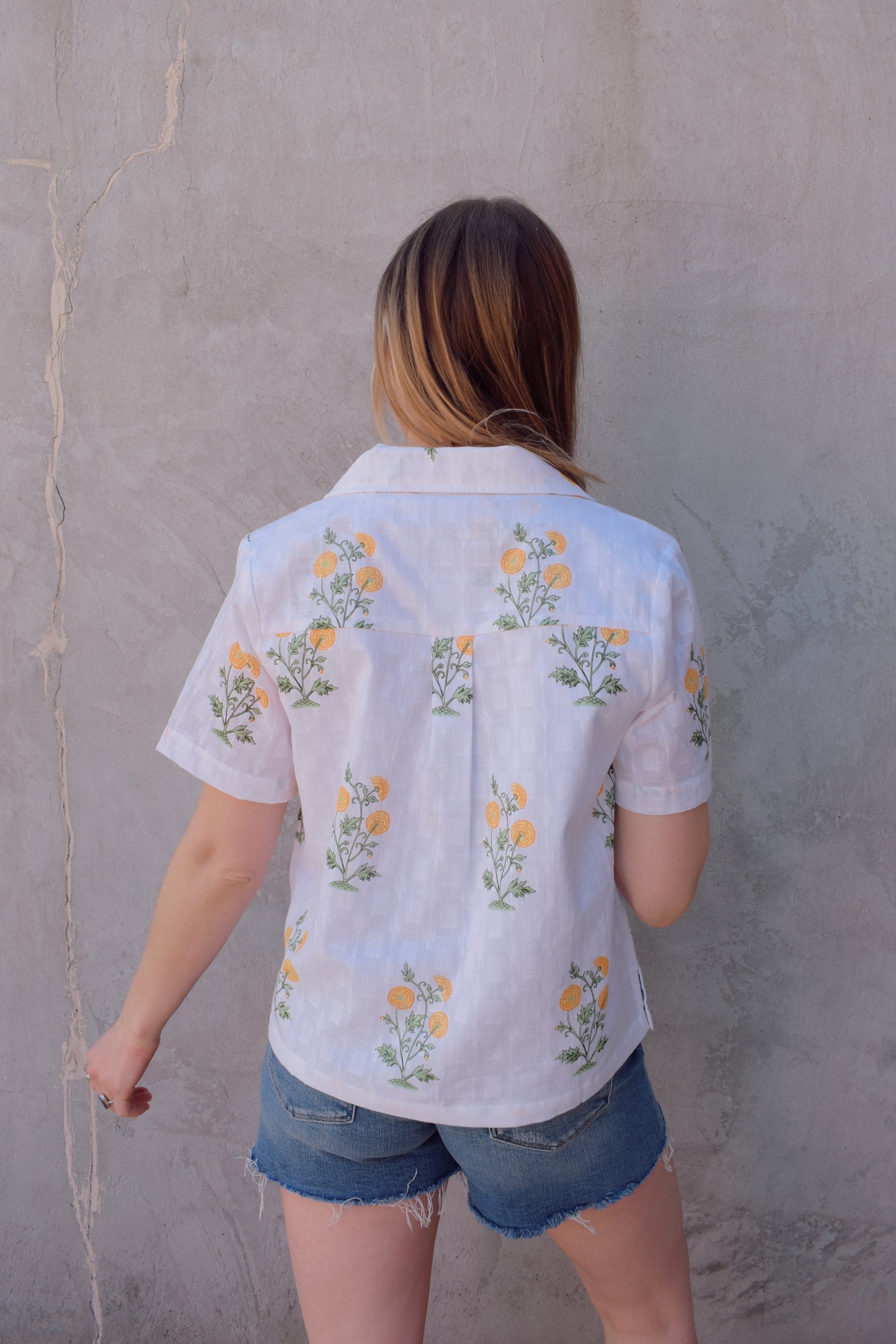 white v neck short sleeve button down with a marigold embroidered pattern. full length, straight fit. 100% cotton