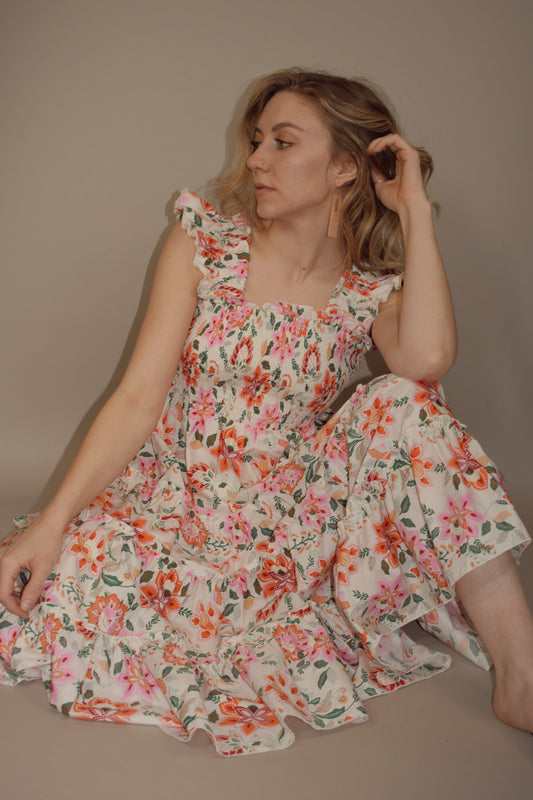 floral midi dress with tiered skirt and ruffle straps with smocking. smocked bodice. square neck and back. greens, pinks, yellow and orange colors for pattern. has pockets