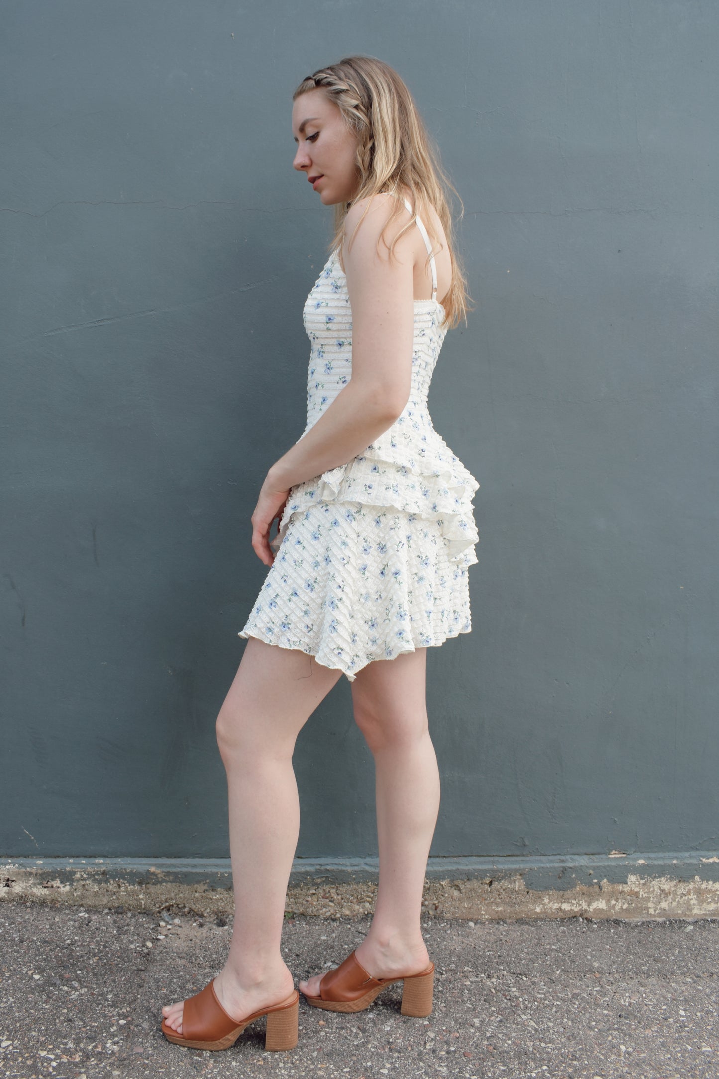 cream mini dress with a blue ditsy floral pattern and mini ruffle fabric, stretchy, back zip enclosure, adjustable spaghetti straps, shark bite tiered skirt, fitted bodice, lined