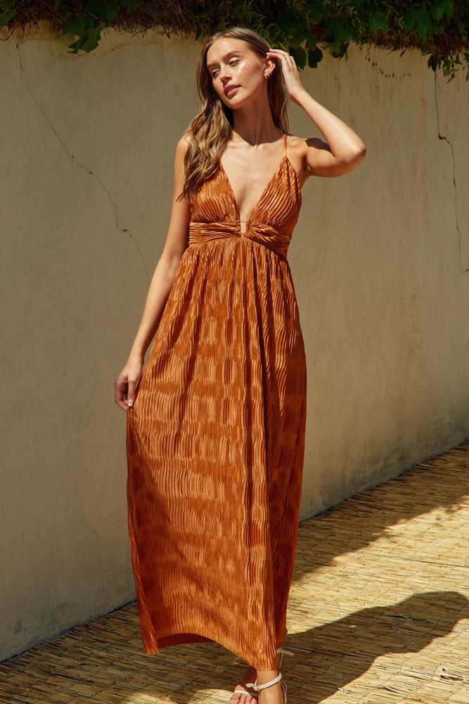 deep v neck spaghetti strap dress with a wavy texture fabric that illuminates when in the sun. maxi dress. straps cross in the back and tie which features a triangle cutout. theres a metal bar that connects the band just under the neckline.