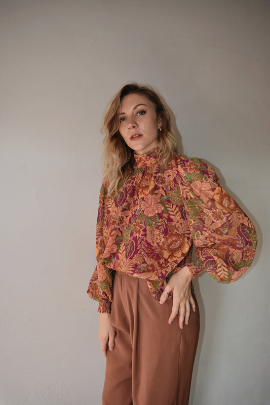 burgundy, green, terracotta (and hits of metallic gold thread) color scheme floral patterned blouse with high neckline, long balloon sleeve with smocked cuff, and back neck button closure. flowy fit and full length