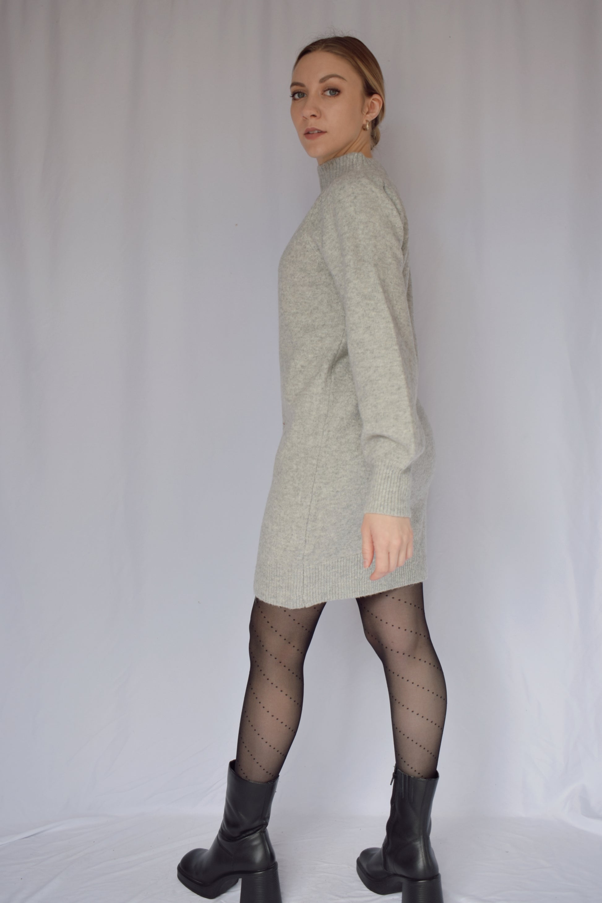 heather gray sweater dress with long sleeves. ribbed cuffs and mock neck with v neck ribbed detail. slight puff on shoulders. hits just above the knees. relaxed fit, not oversized.