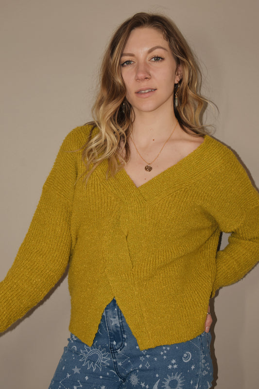golden v neck sweater with twist braid down front and v split on the bottom in the front. cut out on upper back. relaxed fit. 