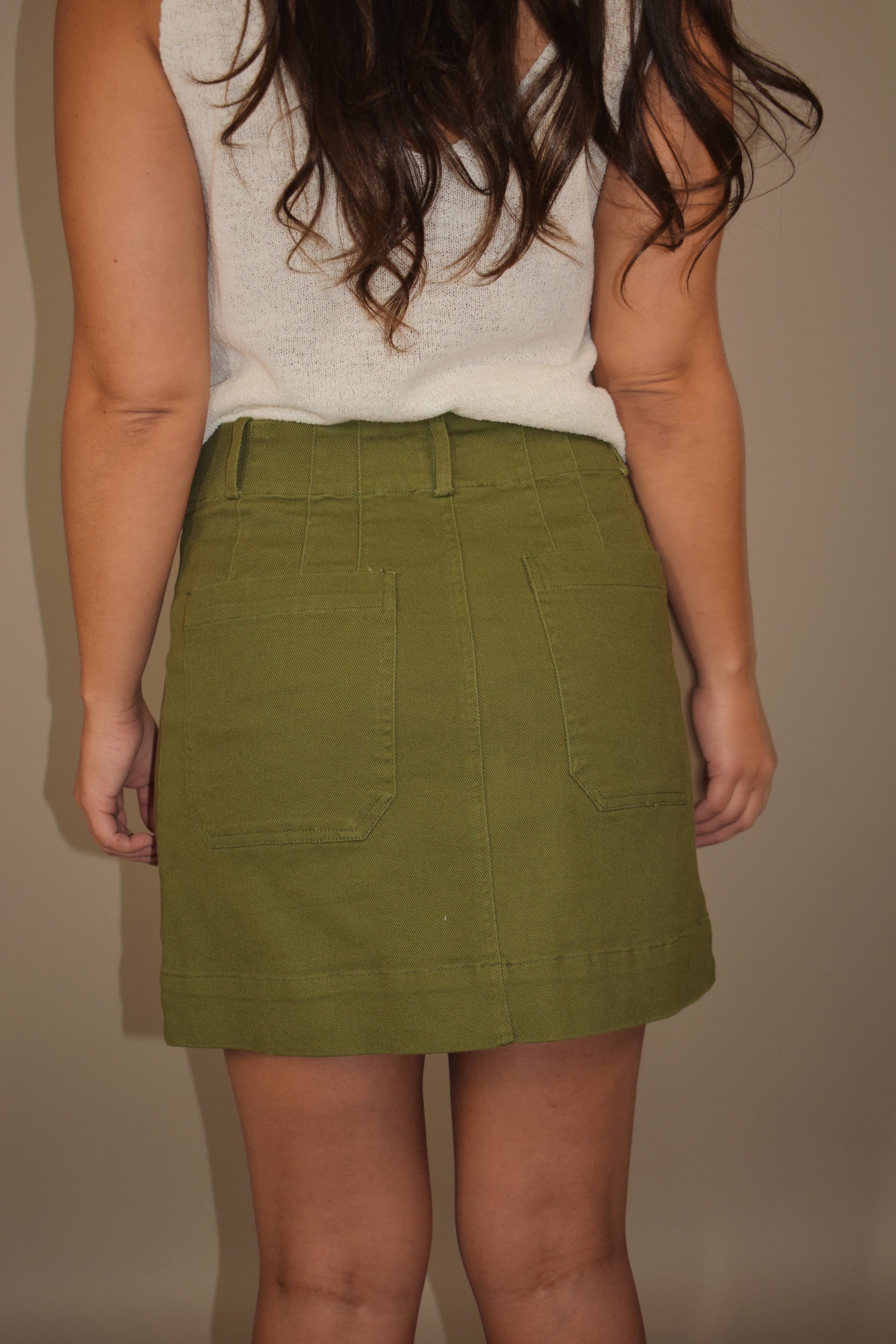 olive mini denim cargo skirt with front patch pockets. zip and button front enclosure. belt loops. has back pockets.