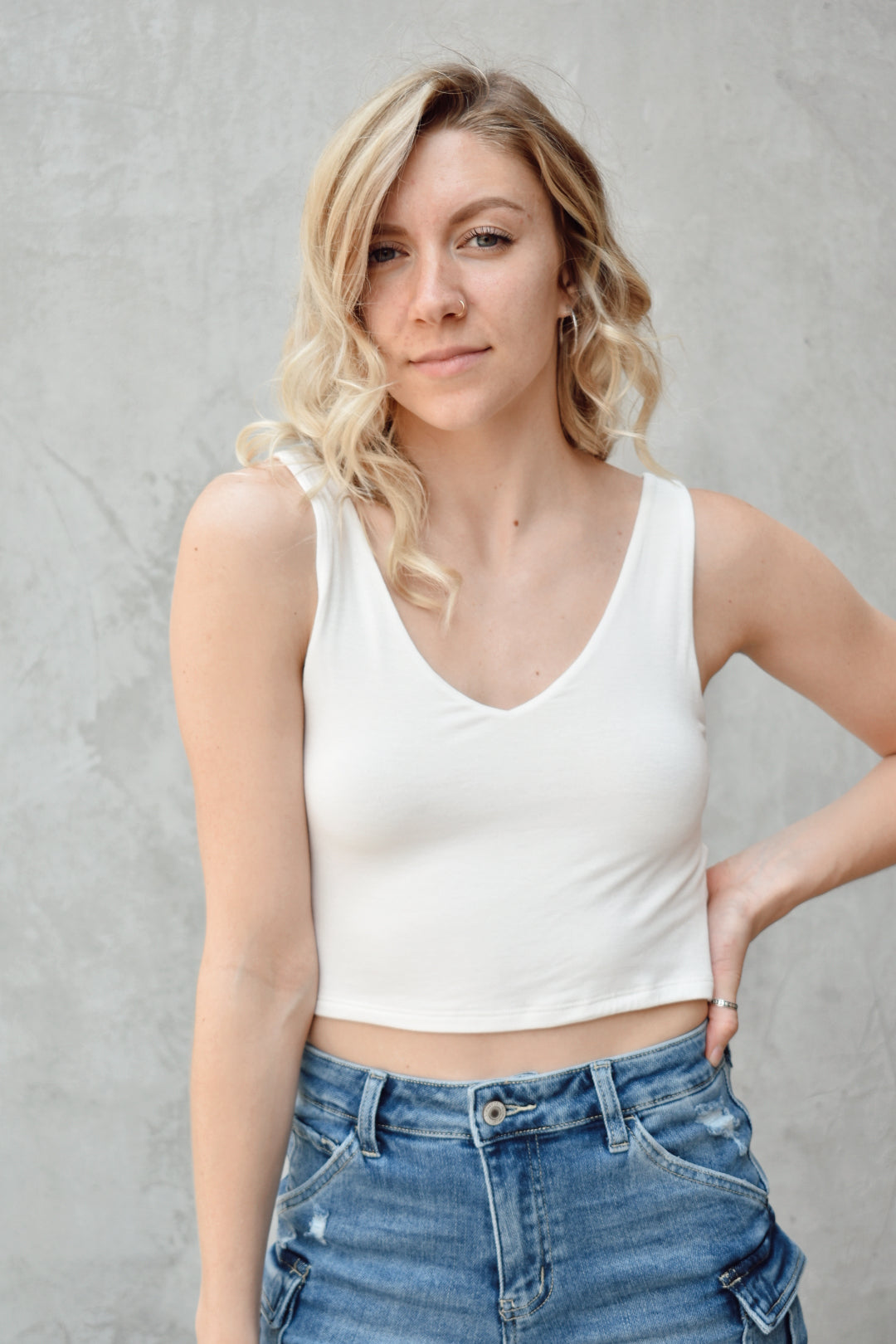White double layered fabric cropped tank. V neck in front, scooped in back. The brand is Hyfve. 