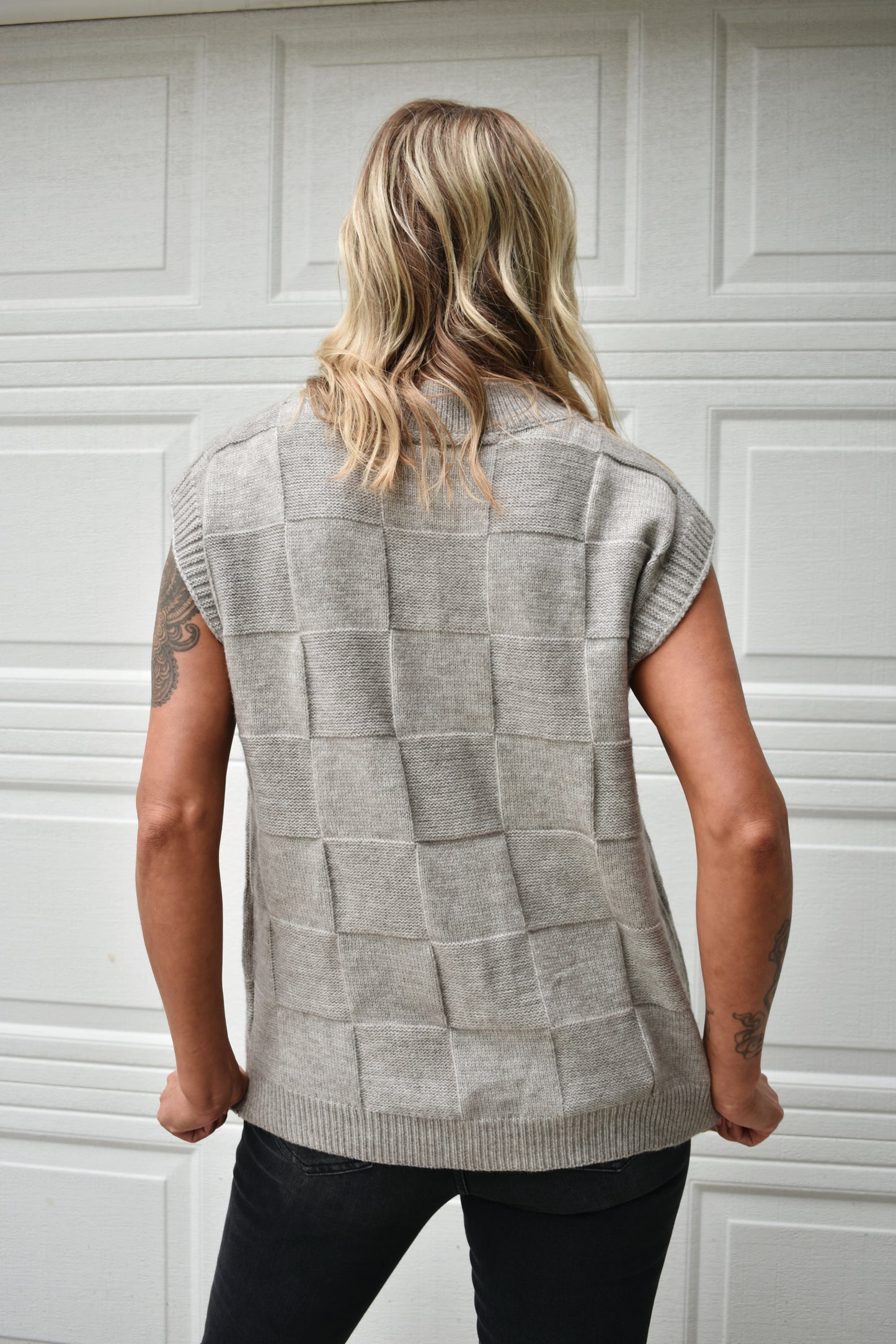 Light grey sweater vest with knit basket weave fabric and ribbed neckline, shoulders, and hem. V-neckline and waist-length cut