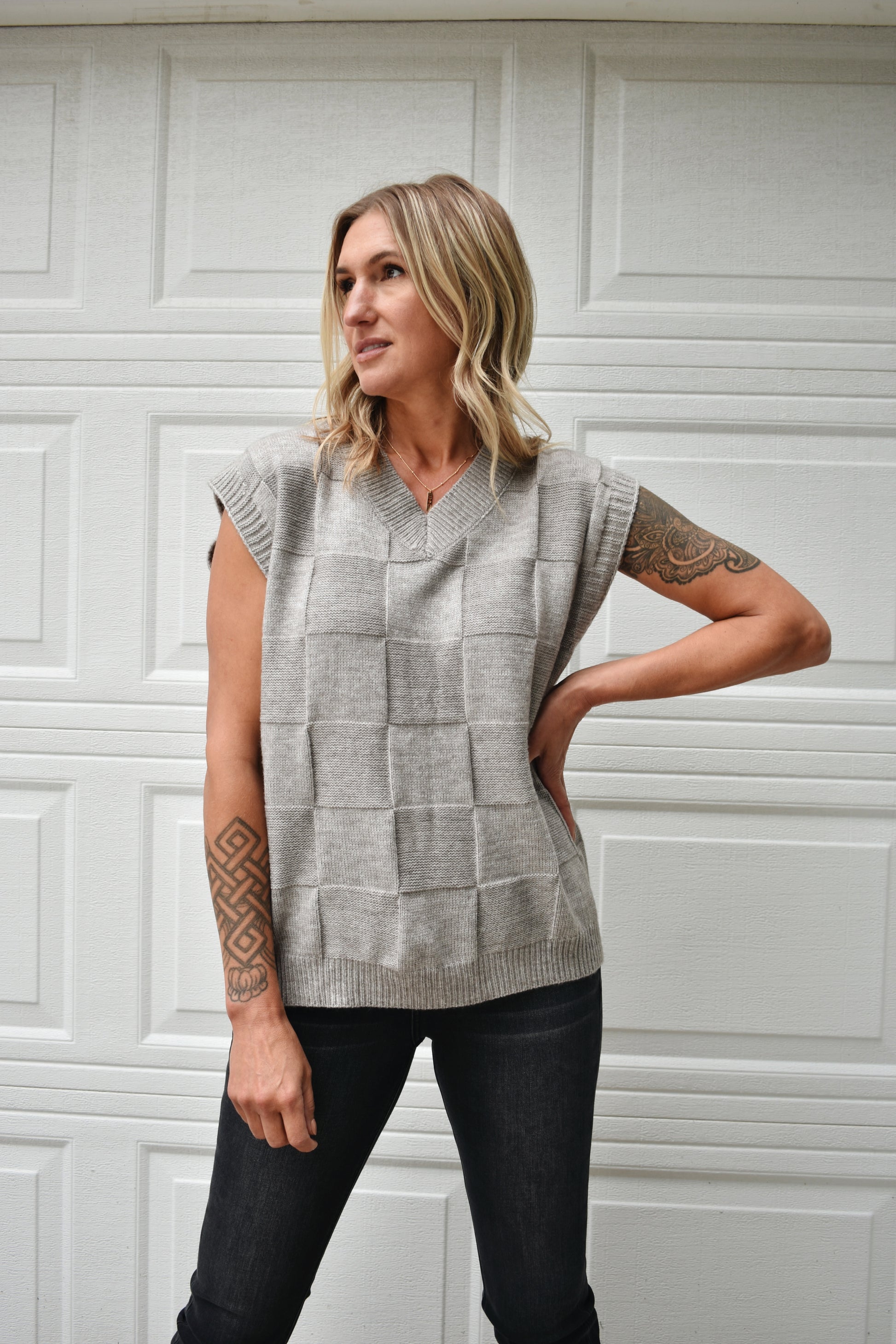 Light grey sweater vest with knit basket weave fabric and ribbed neckline, shoulders, and hem. V-neckline and waist-length cut