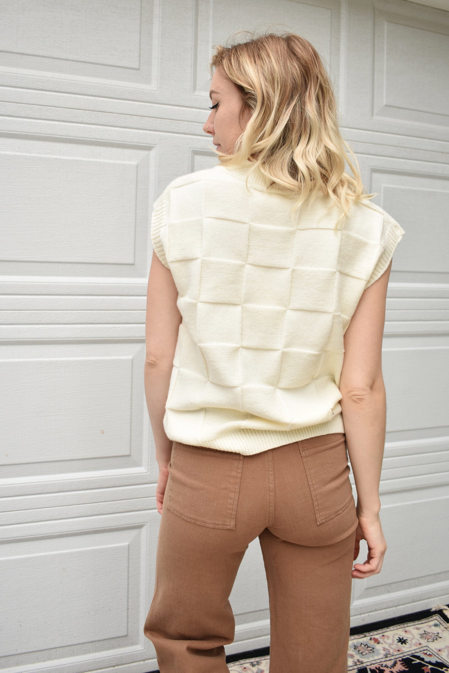 cream sweater vest with knit basket weave fabric and ribbed neckline, shoulders, and hem. V-neckline and waist-length cut