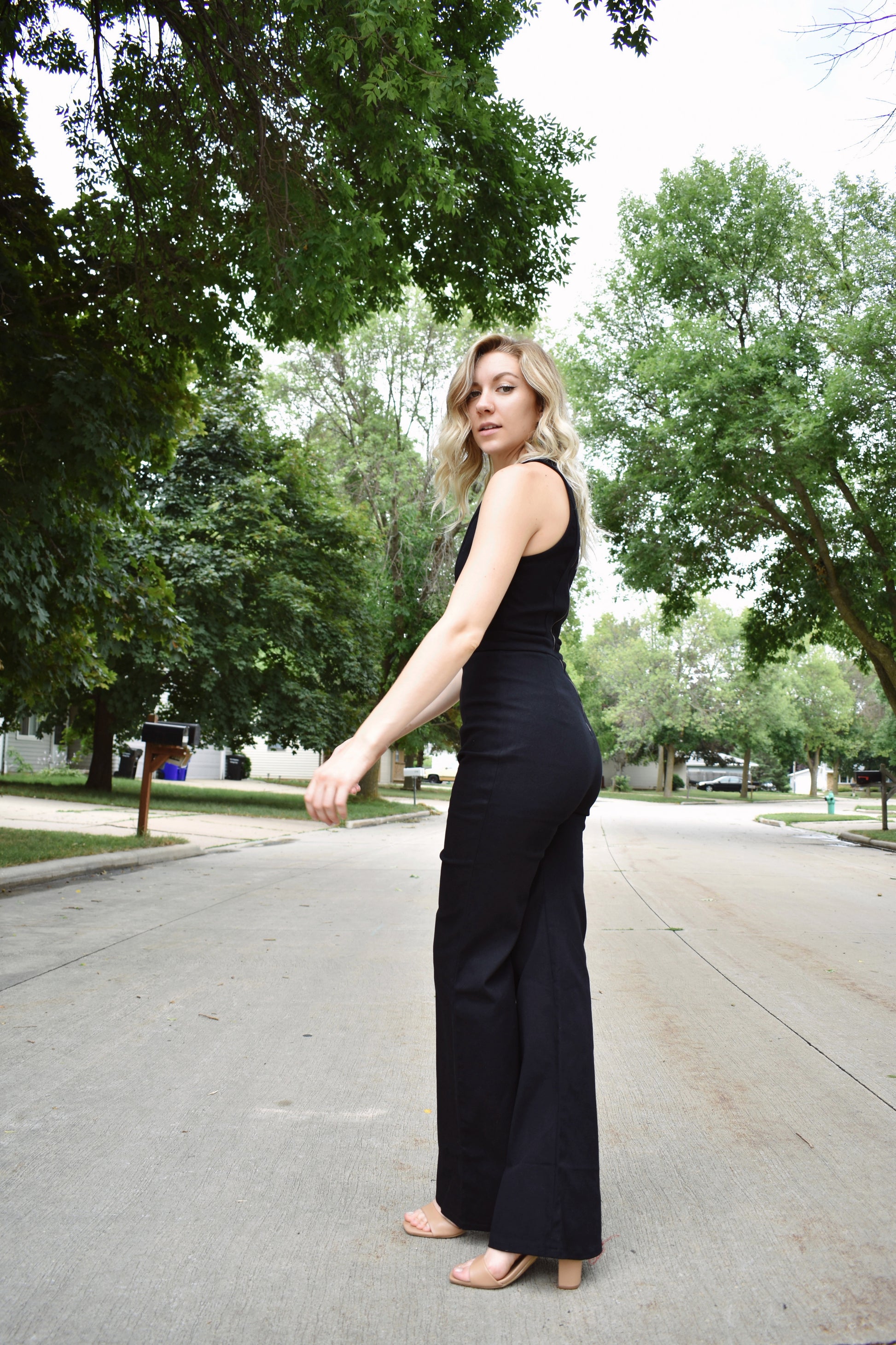 Black denim sleeveless jumpsuit with flared legs and high neck