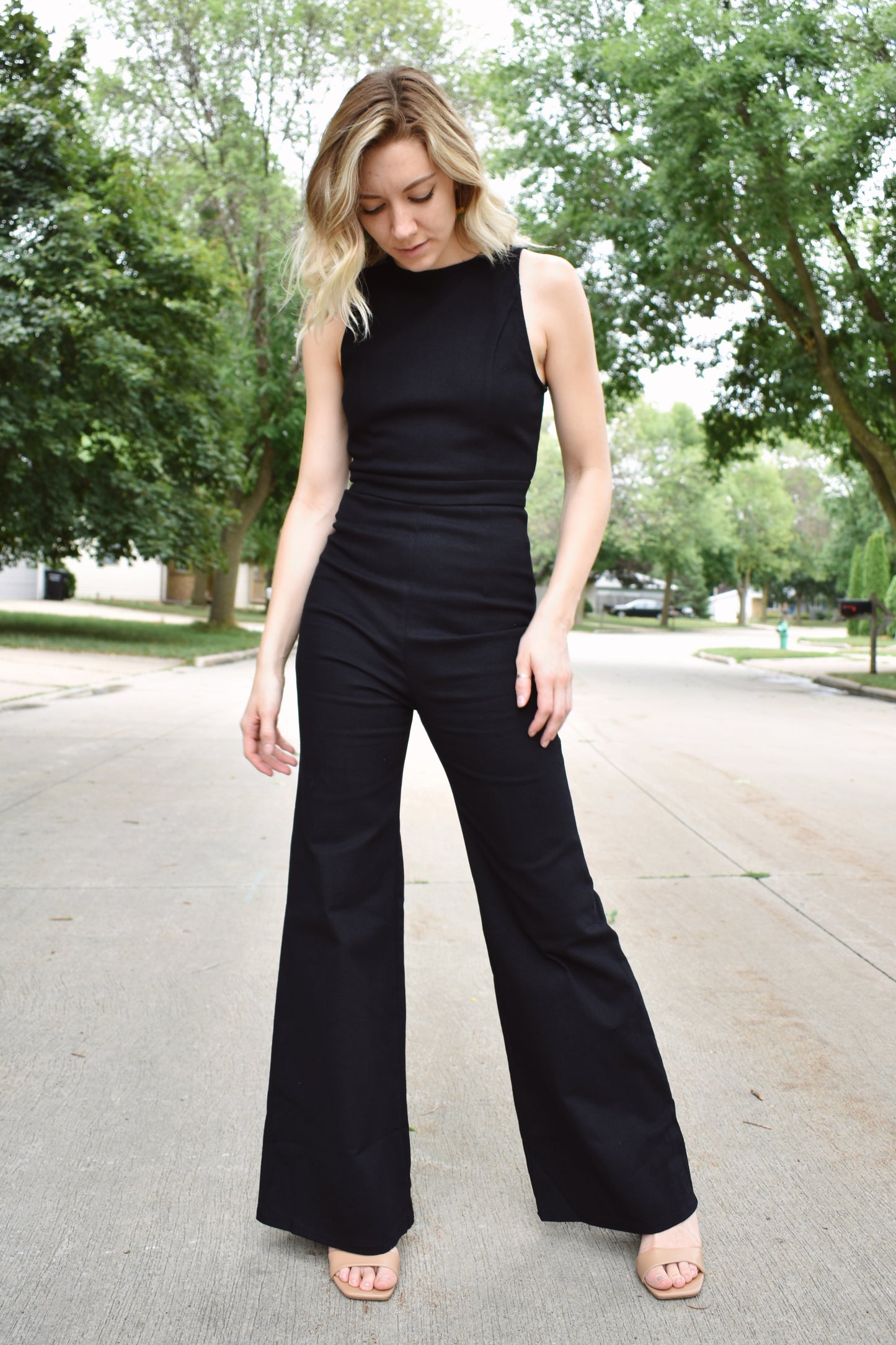 Black denim sleeveless jumpsuit with flared legs and high neck