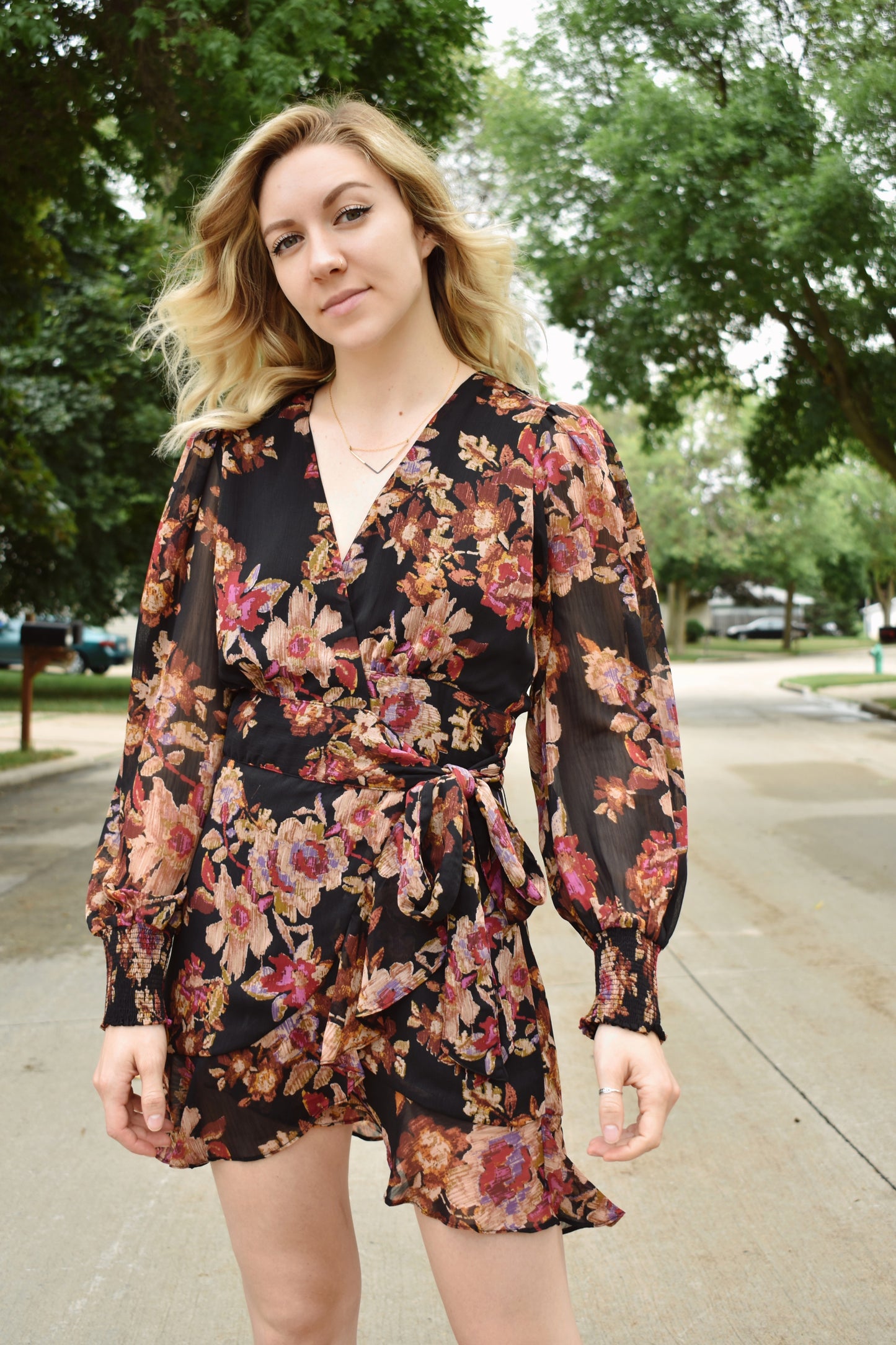 Floral print wrap mini dress with long bishop sleeves that have a smocked opening. Ruffle edged hem.