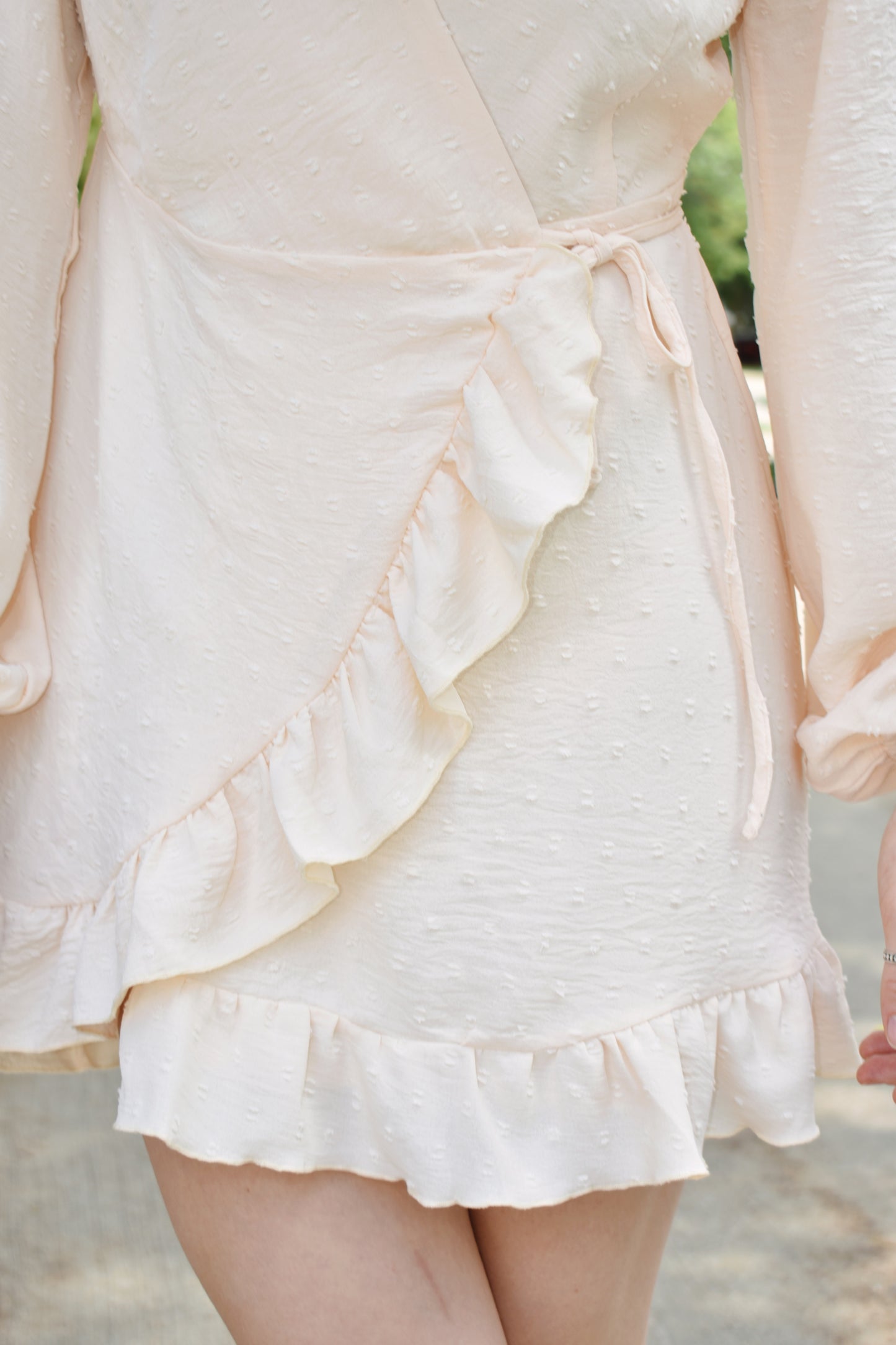 Cream swiss dot textured mini wrap dress with long billow sleeves and ruffled hem