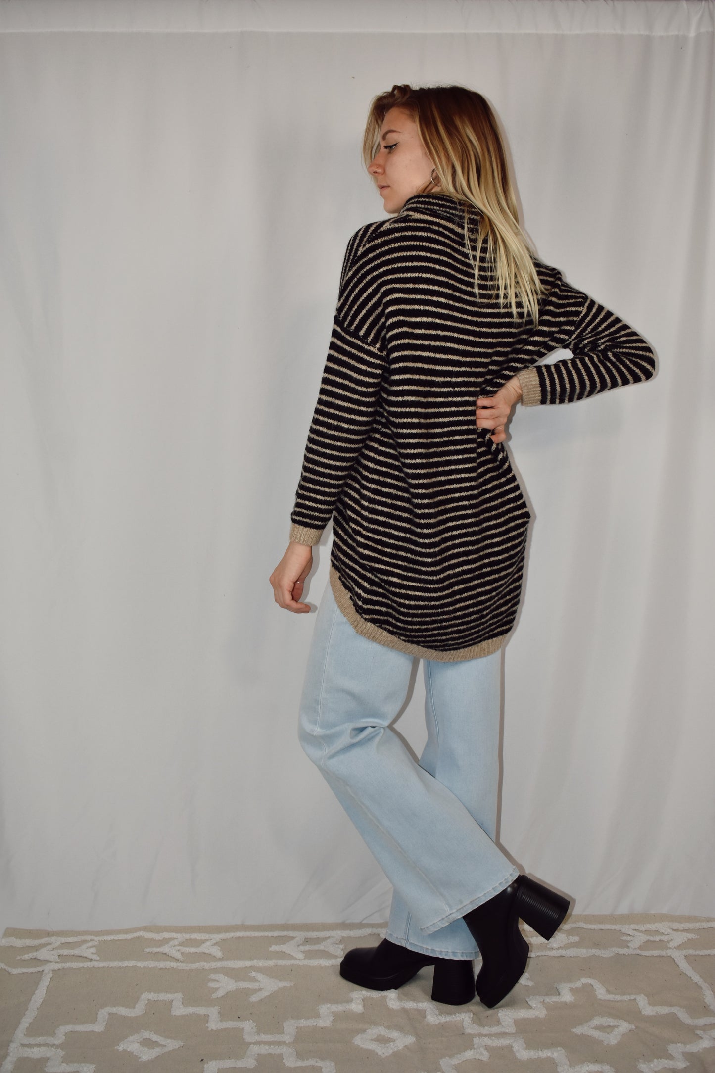 Pullover turtleneck striped sweater. Drop shoulder long sleeves, ribbed hem and sleeve cuffs, and high-low rounded hem. Black and taupe color.