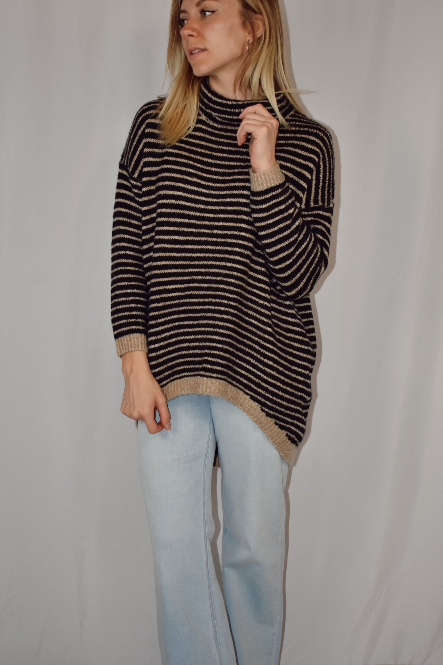 Pullover turtleneck striped sweater. Drop shoulder long sleeves, ribbed hem and sleeve cuffs, and high-low rounded hem. Black and taupe color.