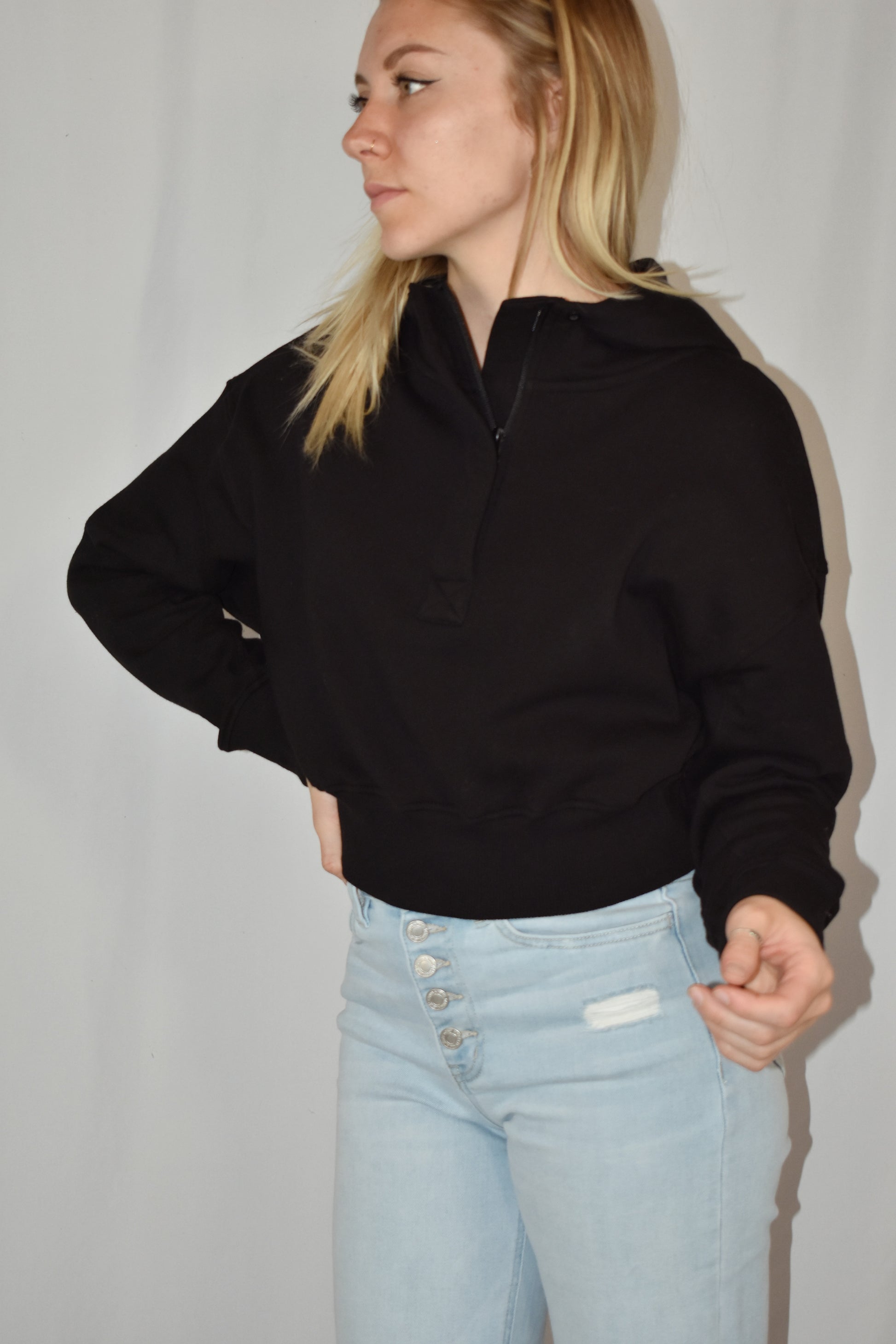 Cropped black hoodie with half placket zip with button closure at neckline. Ribbed cuffs and fleece lining.
